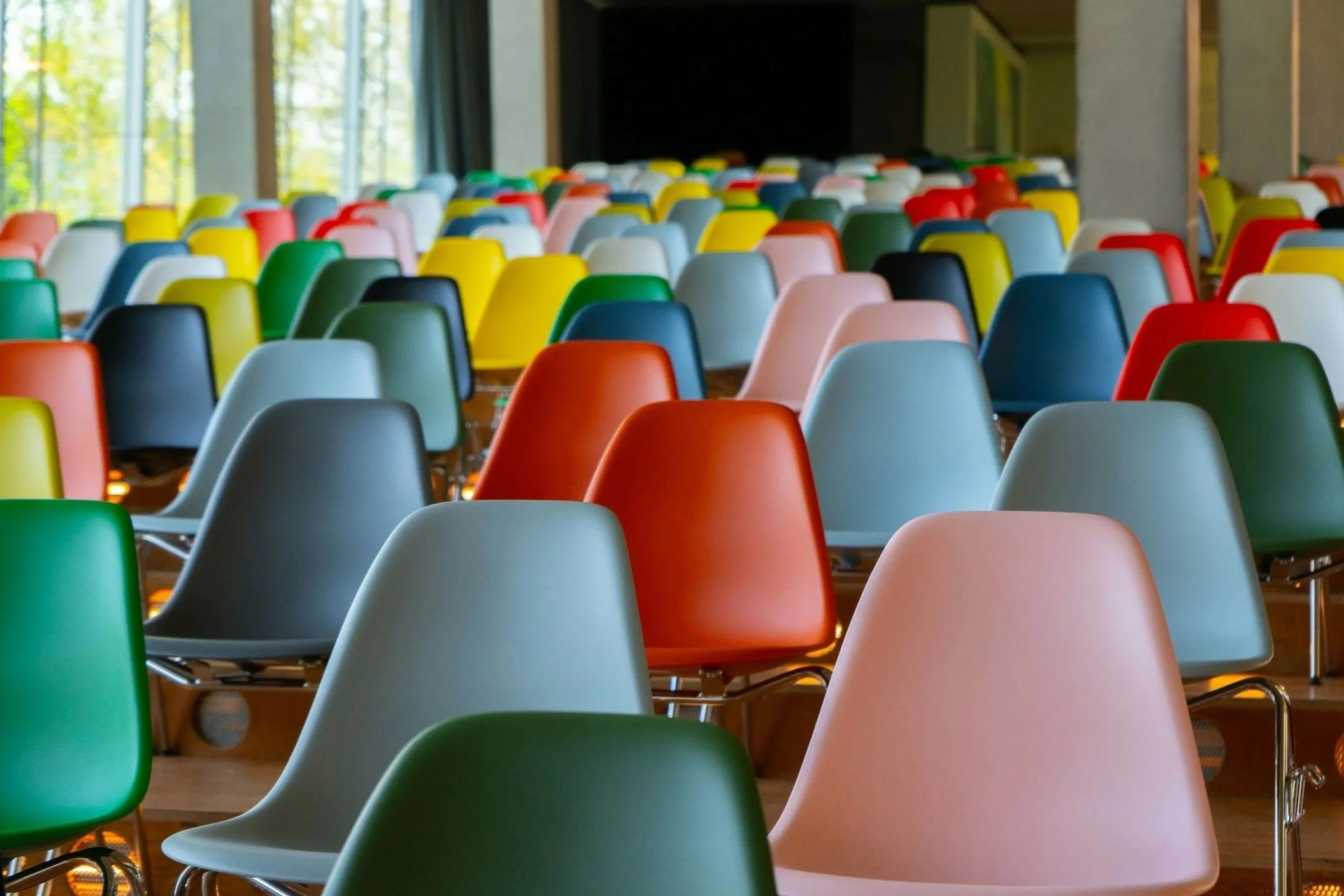 photo of multicolored molded plastic chairs set up as an audience 