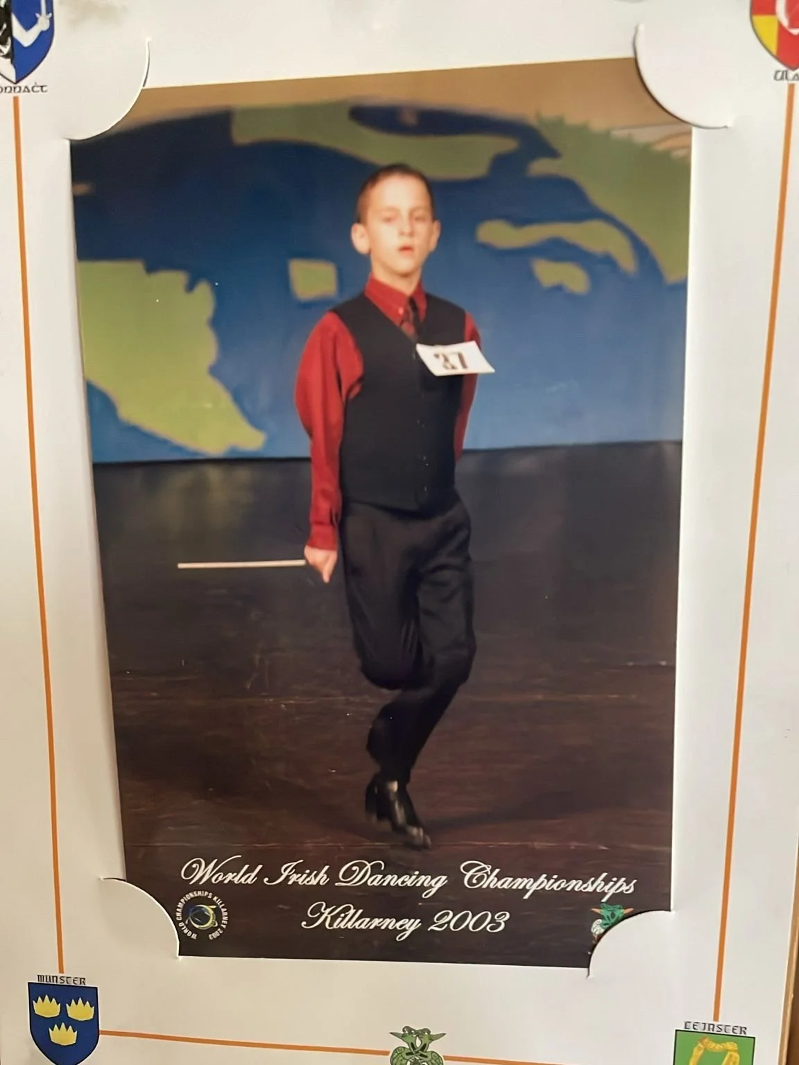 Young dancer participating in World Irish Dancing Championships, Killarney 2003, wearing red shirt and black vest.