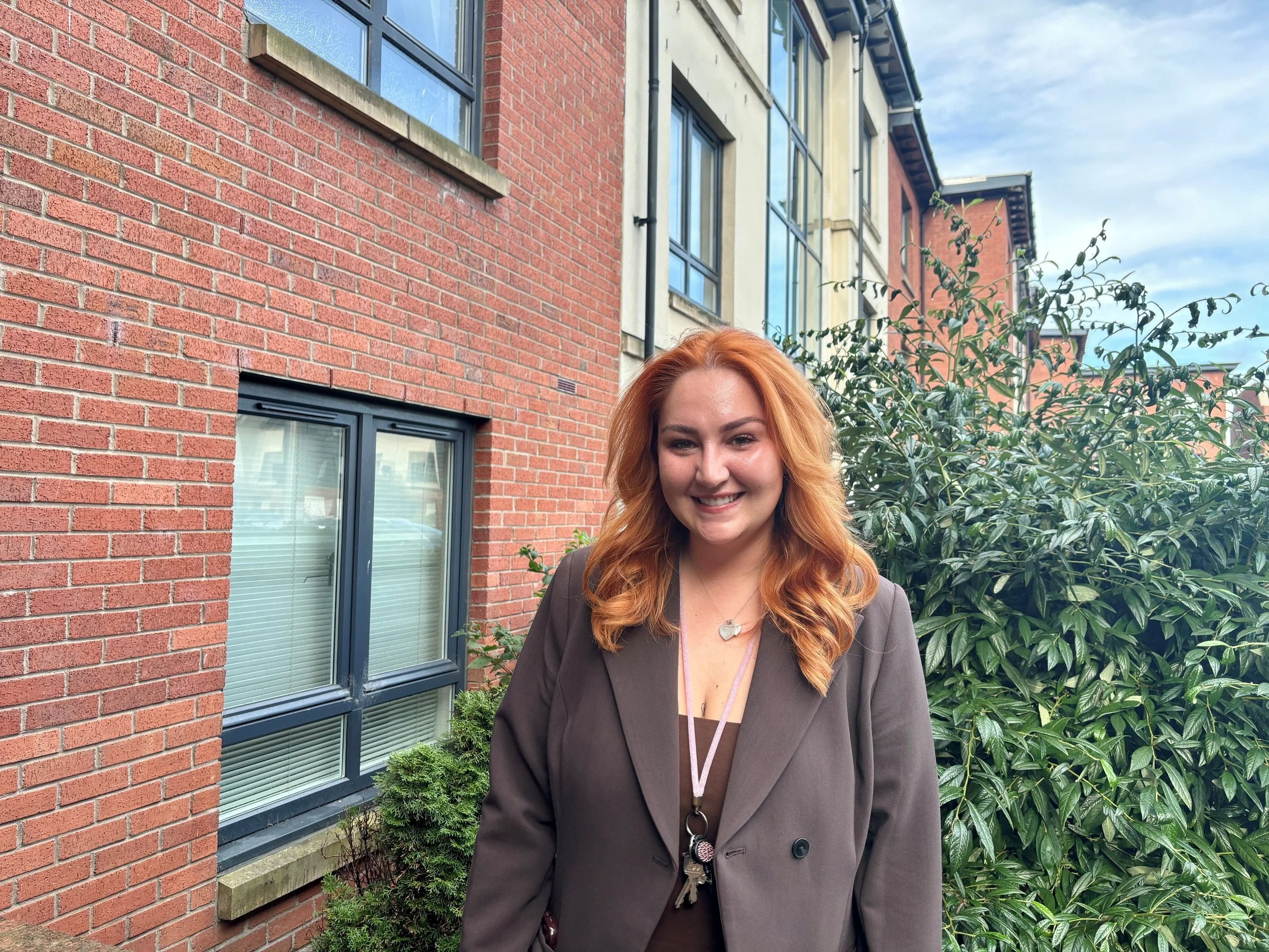 Jessica Rae, Client Relationship Manager outside a black of flats in Edinburgh.