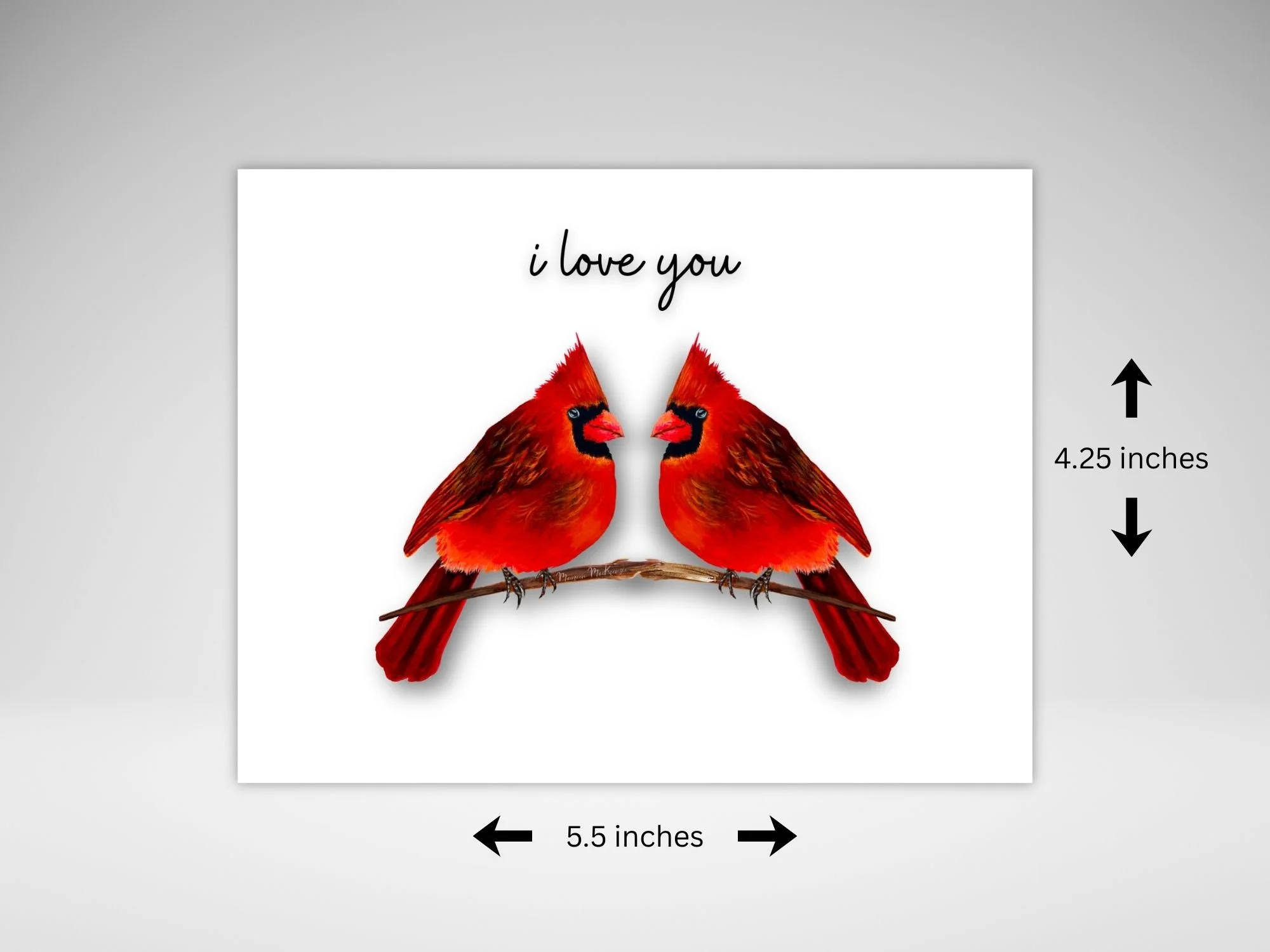 A greeting card by  Maureen Mackenzie featuring two red cardinals perched facing each other on a  branch, set against a  white background. The words I Love You is written just above their heads.