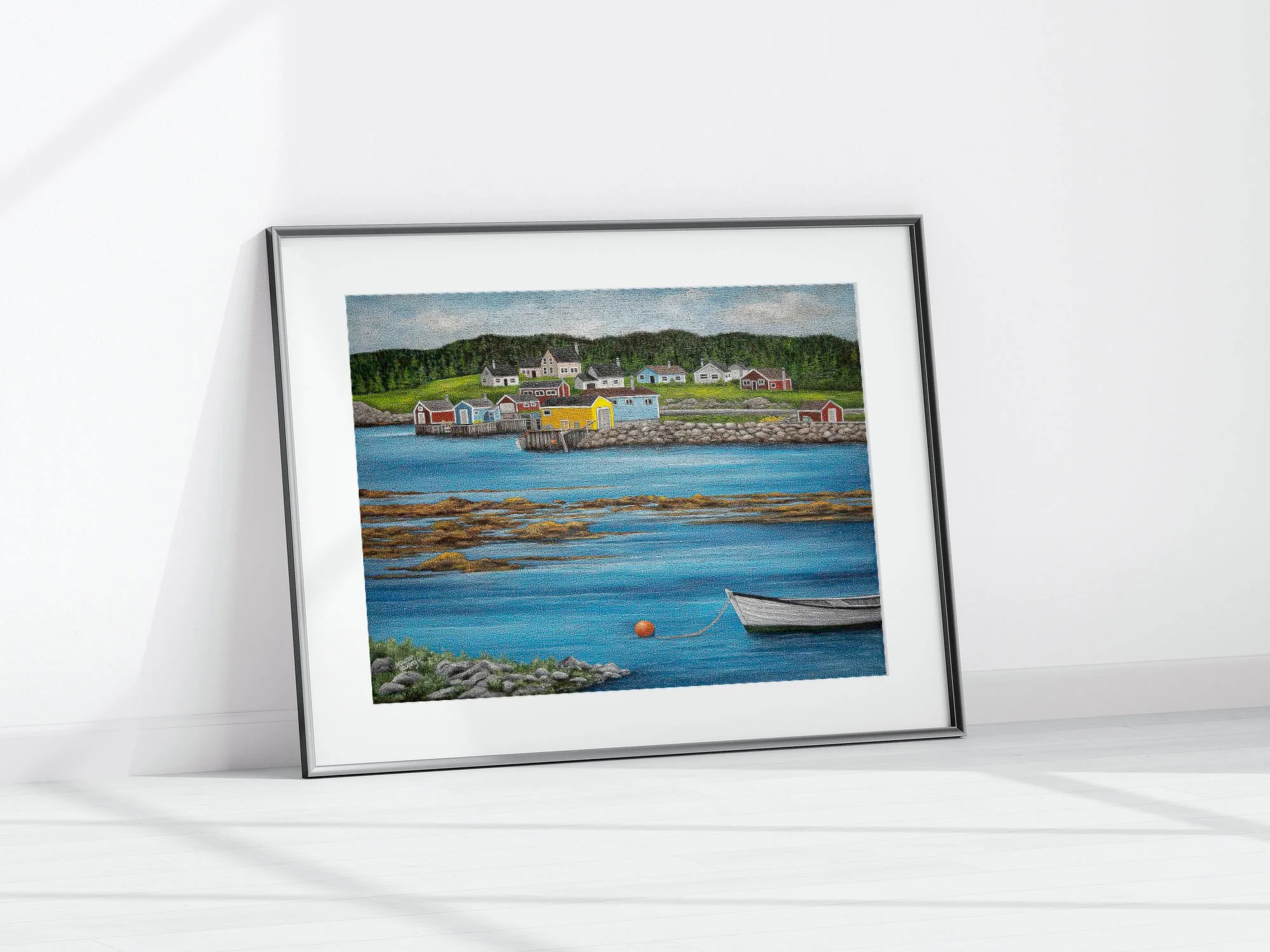 A print by Maureen MacKenzie featuring a colourful coastal newfoundland village, calm blue waters, seaweed flowing over rocks and a white fishing skiff moored to an orange fishing buoy..