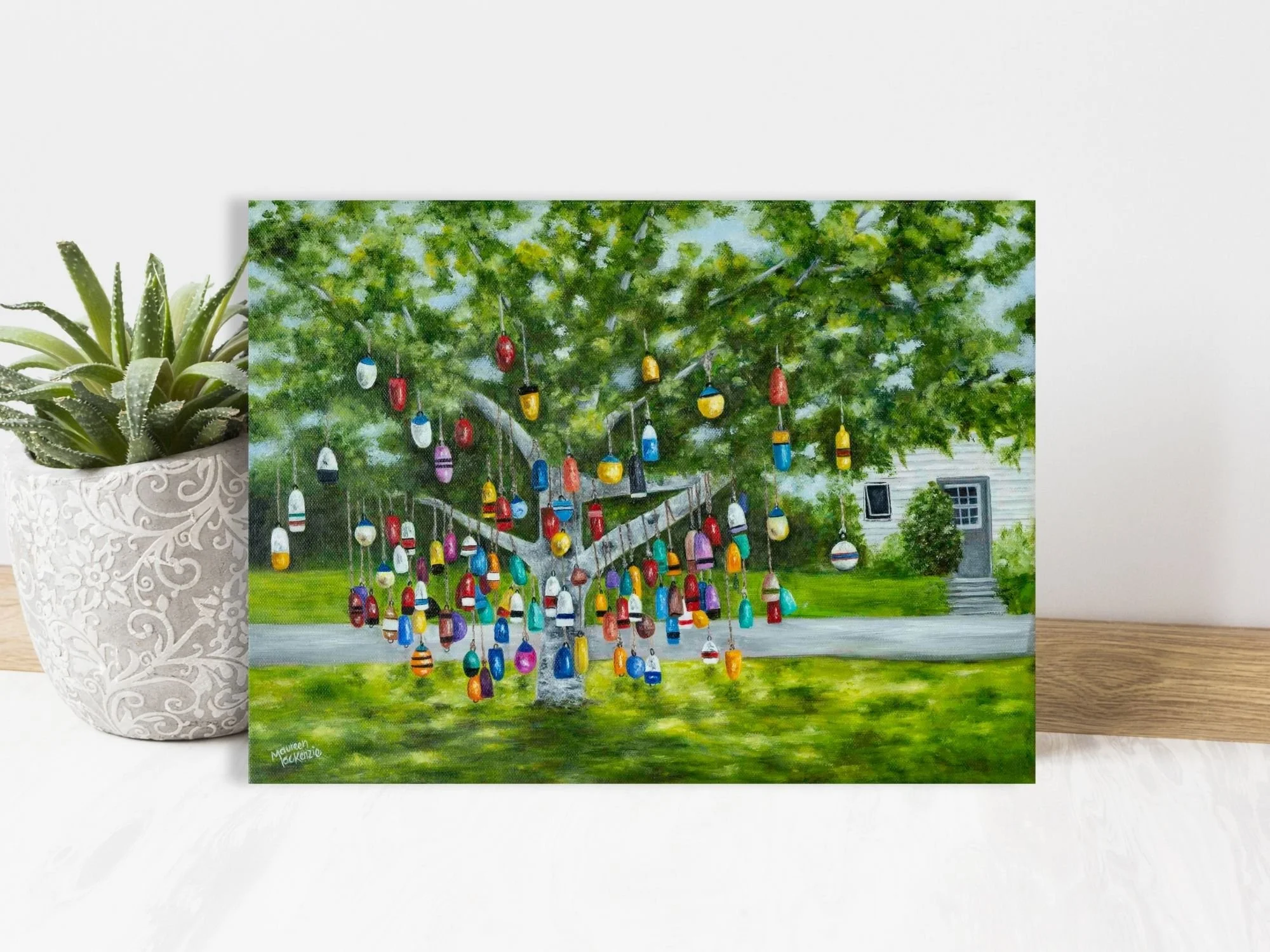 Original 12x16 oil painting of a colourful buoy tree in Prince Edward Island, featuring hanging fishing buoys beneath a leafy green tree in a coastal Maritime setting.