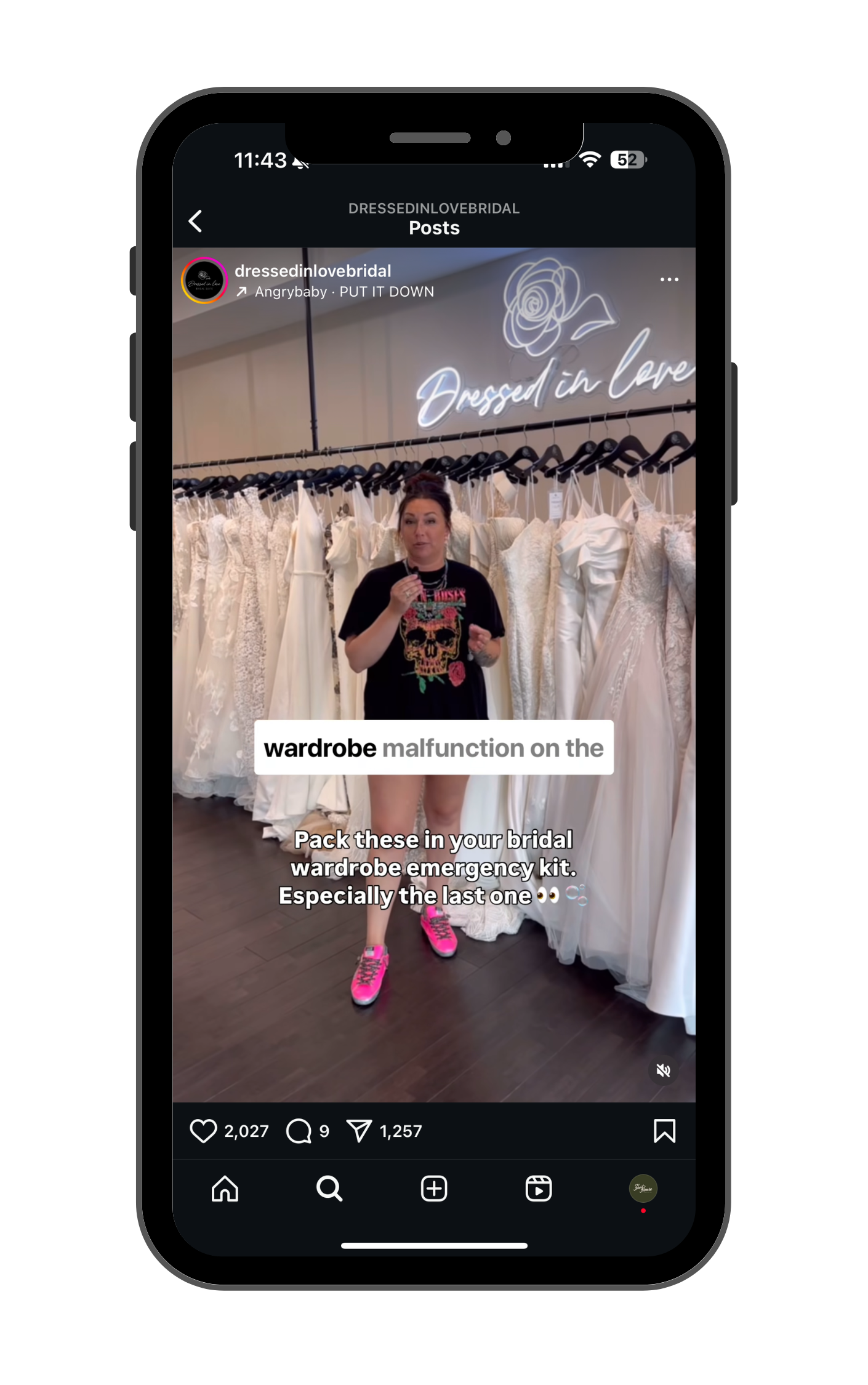 A woman standing in front of wedding dresses hanging on a rack inside a bridal boutique, with a neon sign that reads 'Dressed in Love' behind her.
