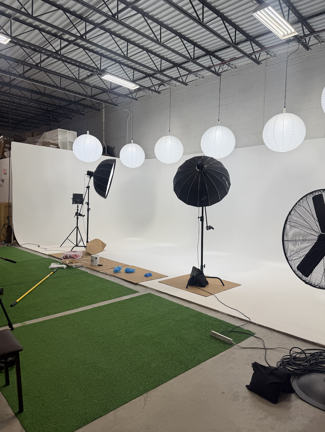 Photography studio setup with white background, lighting equipment, and paper lanterns hanging from the ceiling.