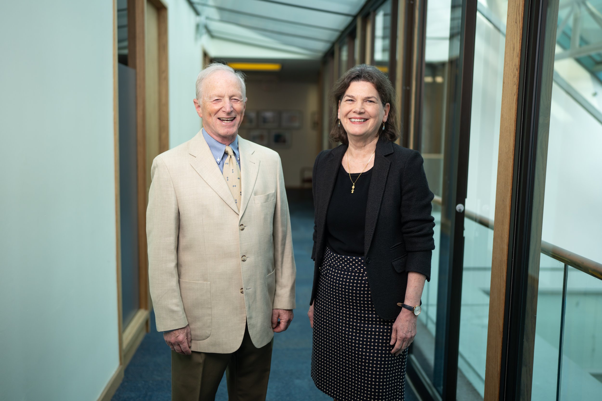 Two people, Anne and Mark, standing in a hallway smiling at the camera
