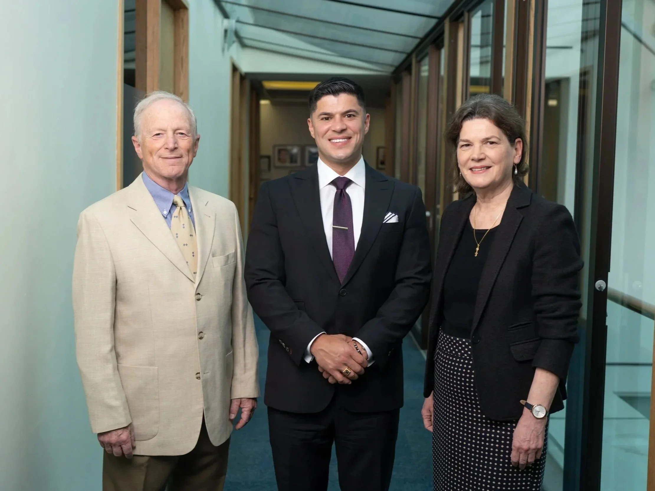 Three people standing in a hallway smiling at the camera