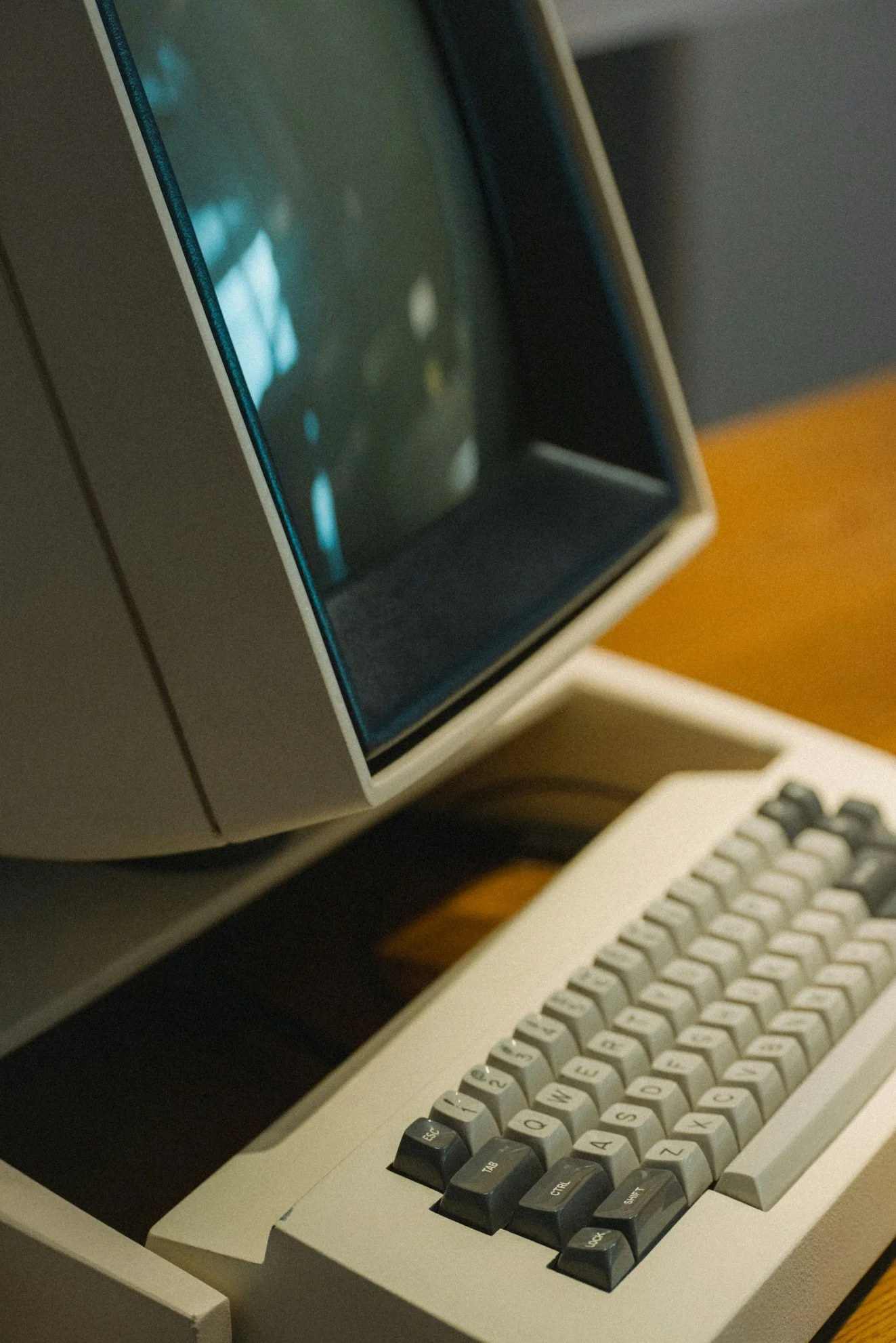Close-up of a vintage computer with a built-in screen and a beige keyboard, resembling an old terminal or early personal computer.