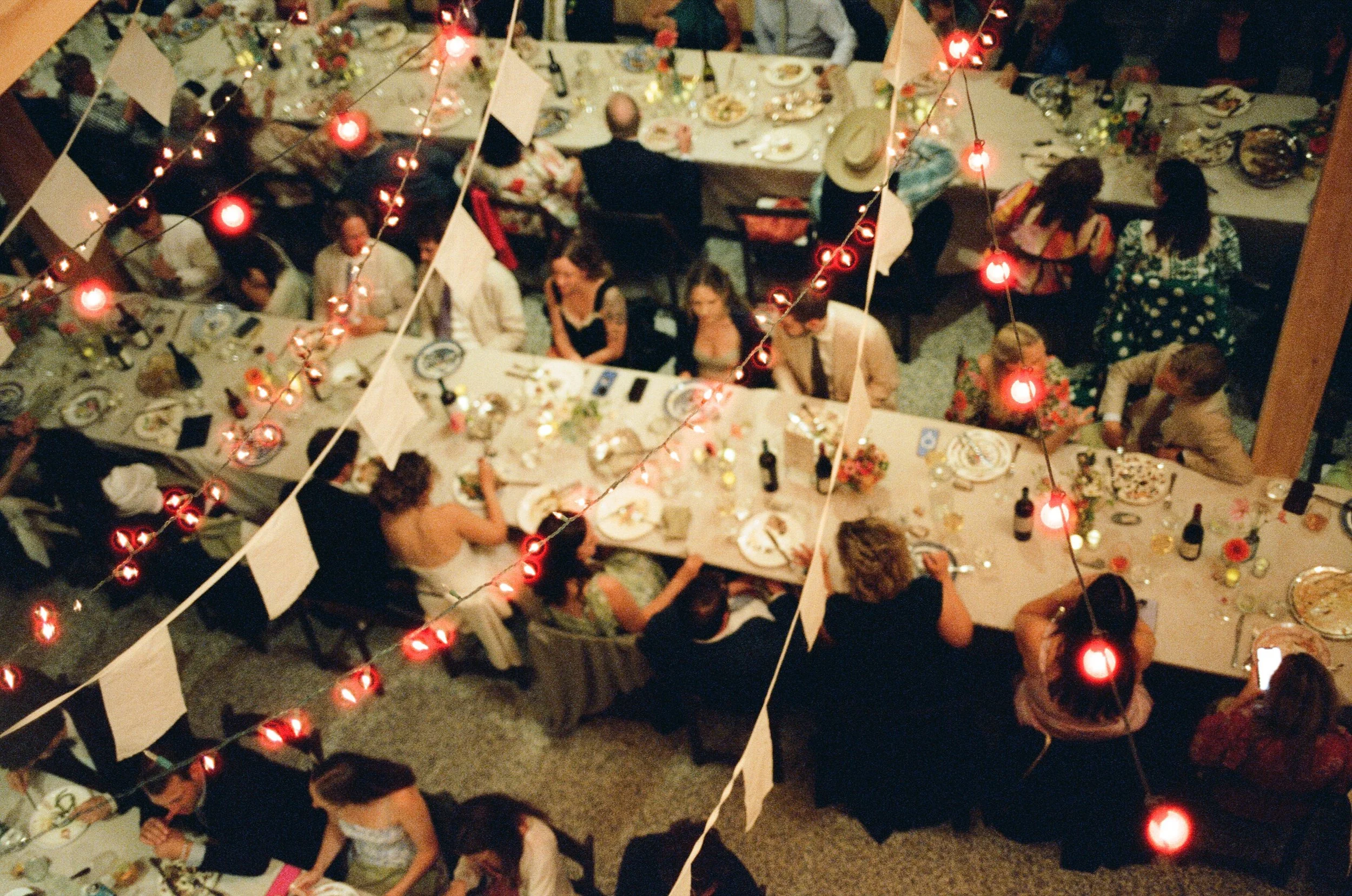 guests eating dinner on long tables in a barn from above