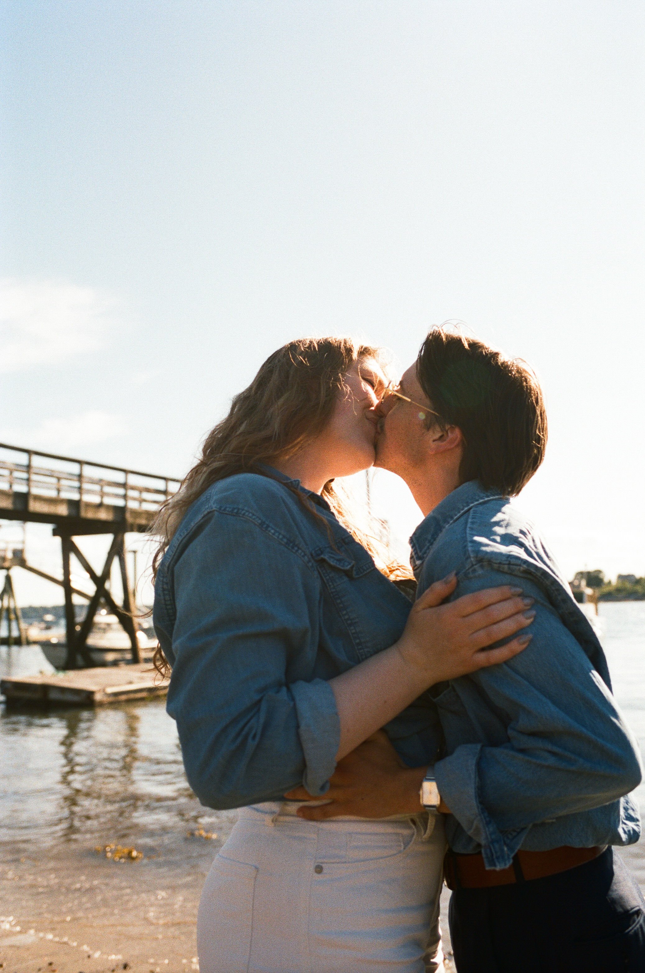 an lgbt+ couple kissing on a beach in portland maine