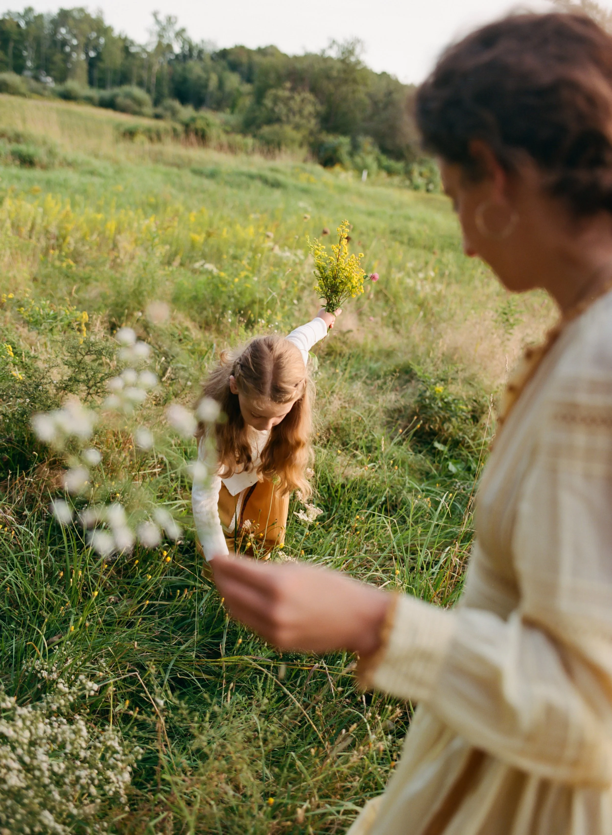 Mom and daughter photography gathering flowers in a field in maine
