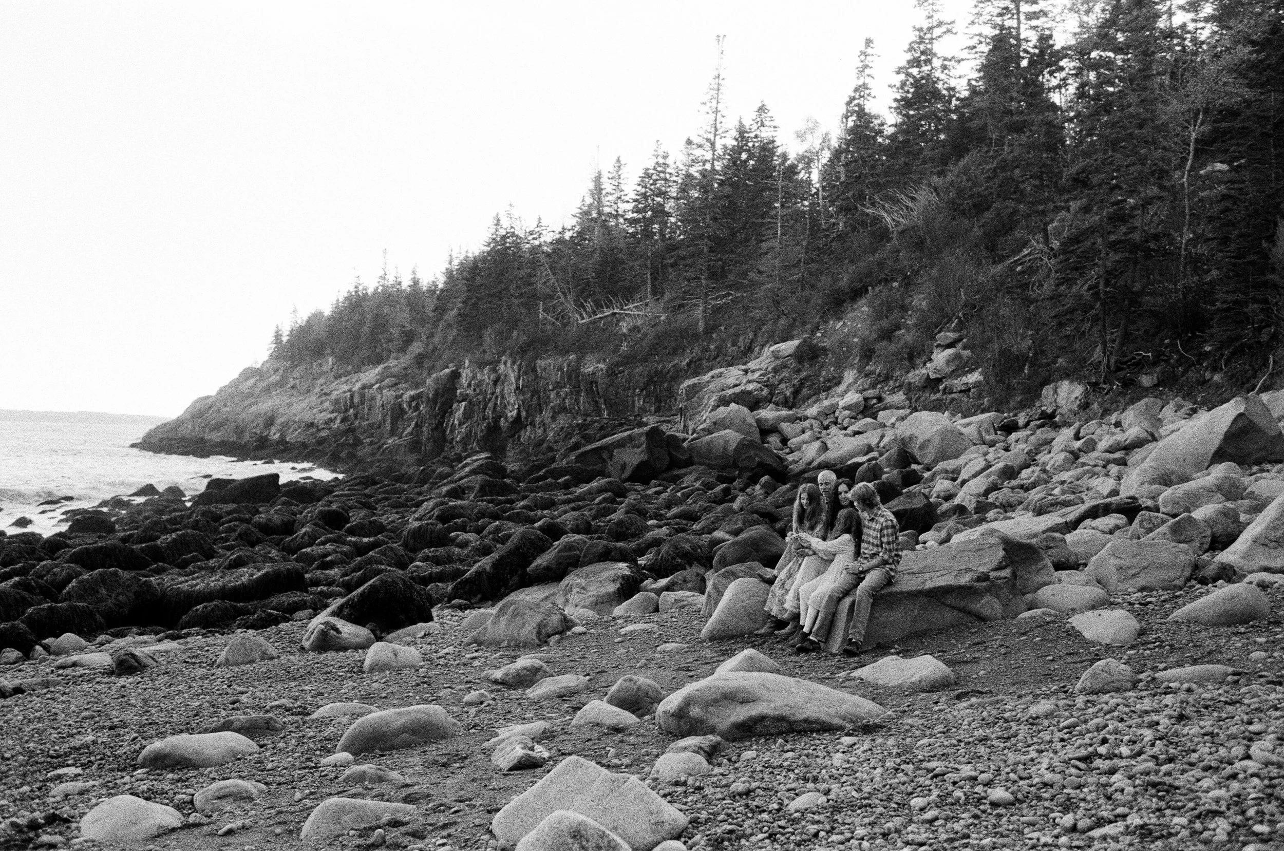 a family sits on a rocky beach on film in maine