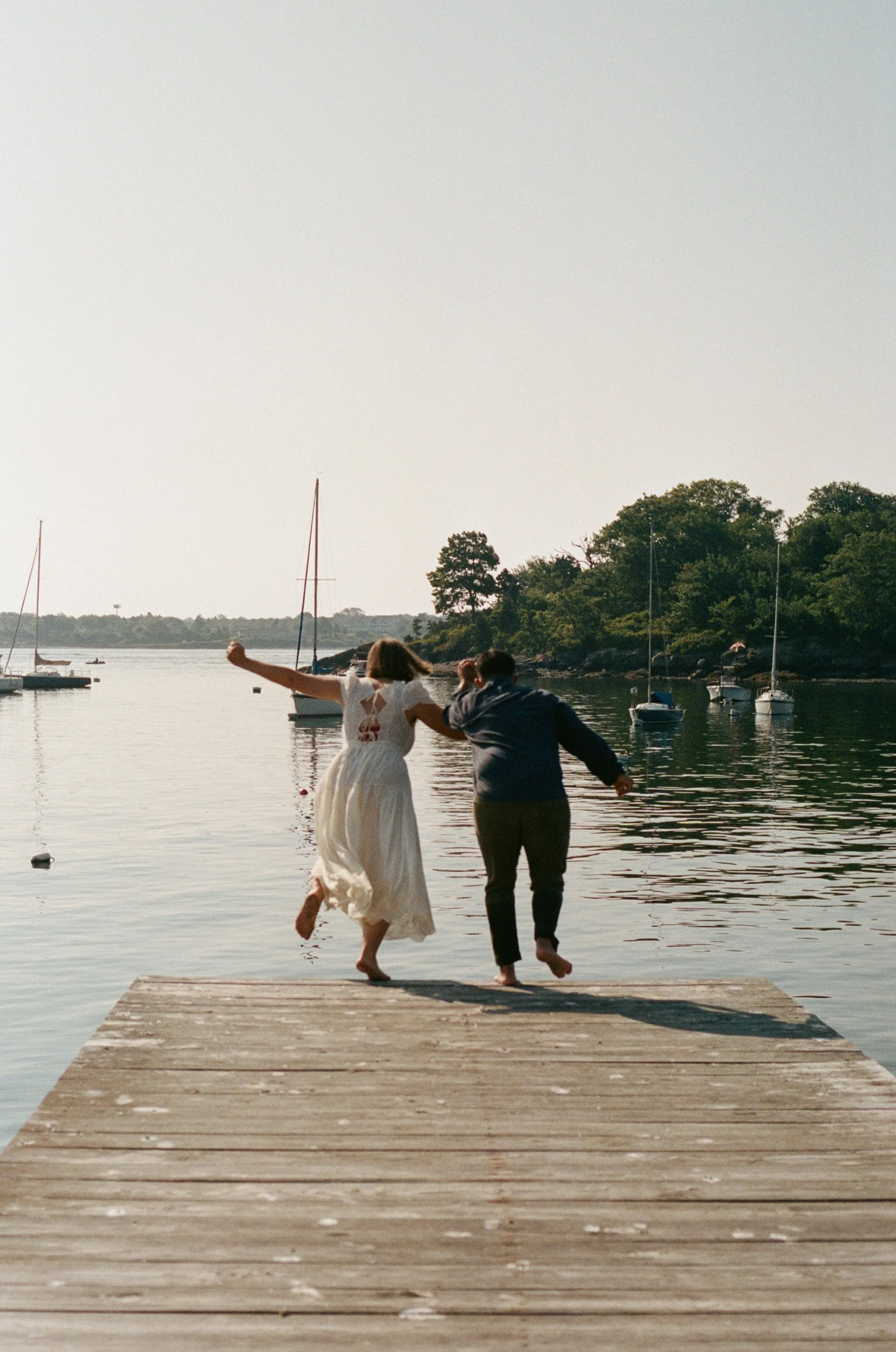 couple jumping off dock morning of wedding