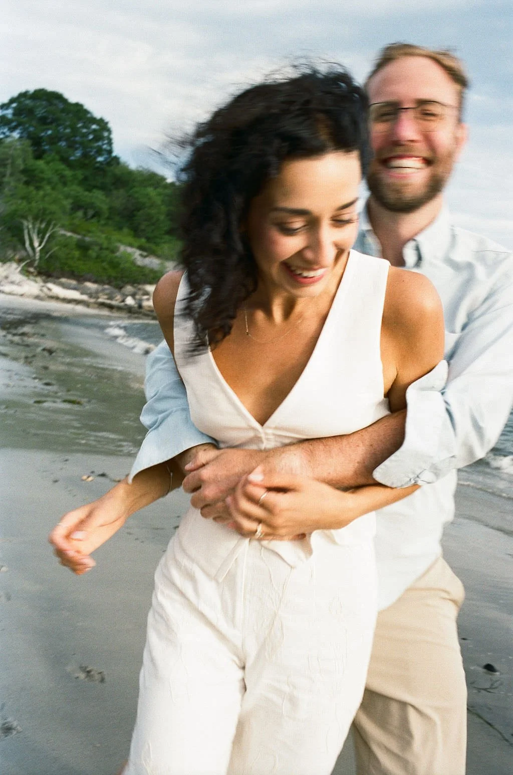 couple laughing together during beach engagement session in portland