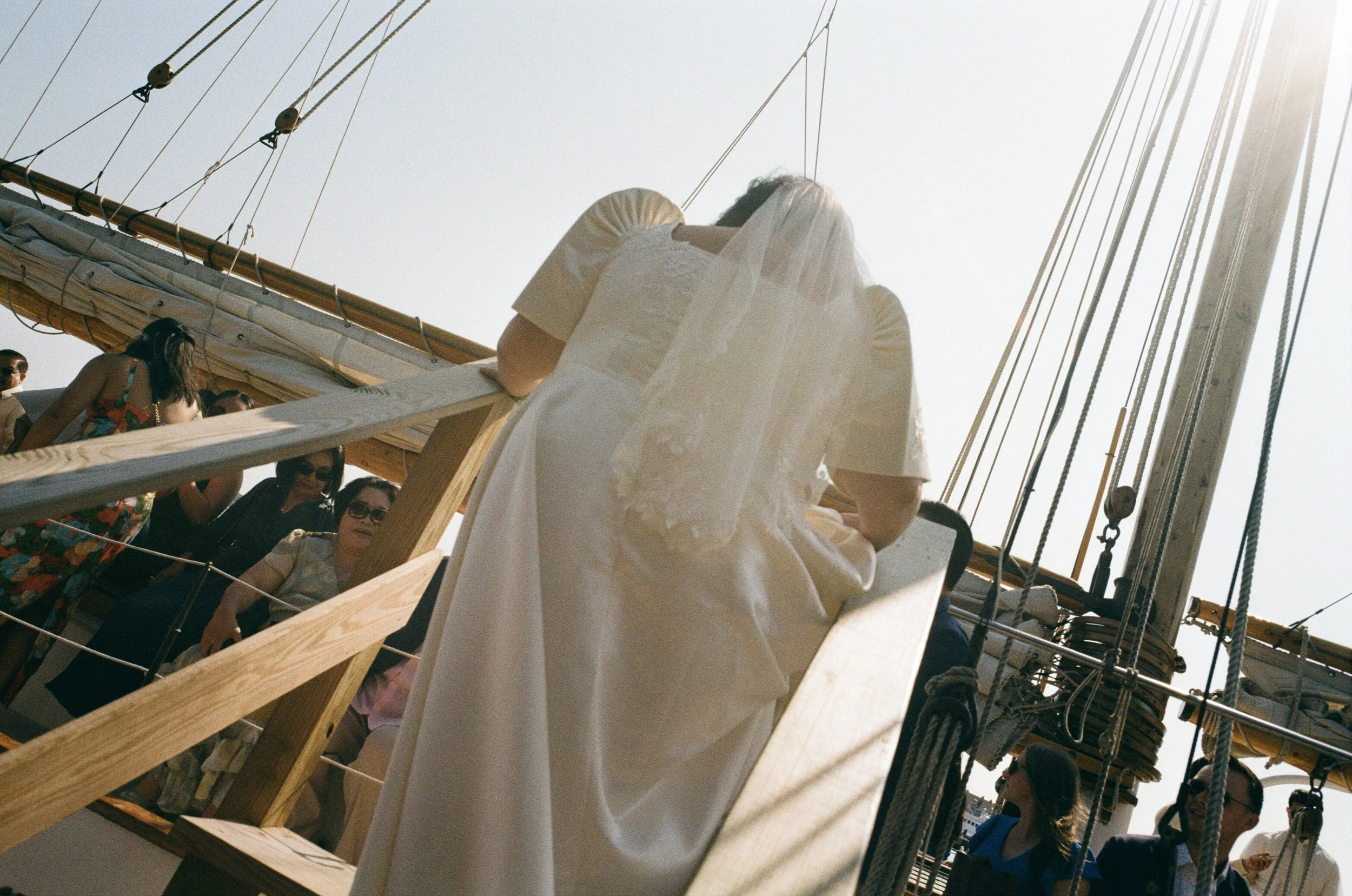 bride wearing traditional filipino wedding dress getting onto schooner during maine wedding