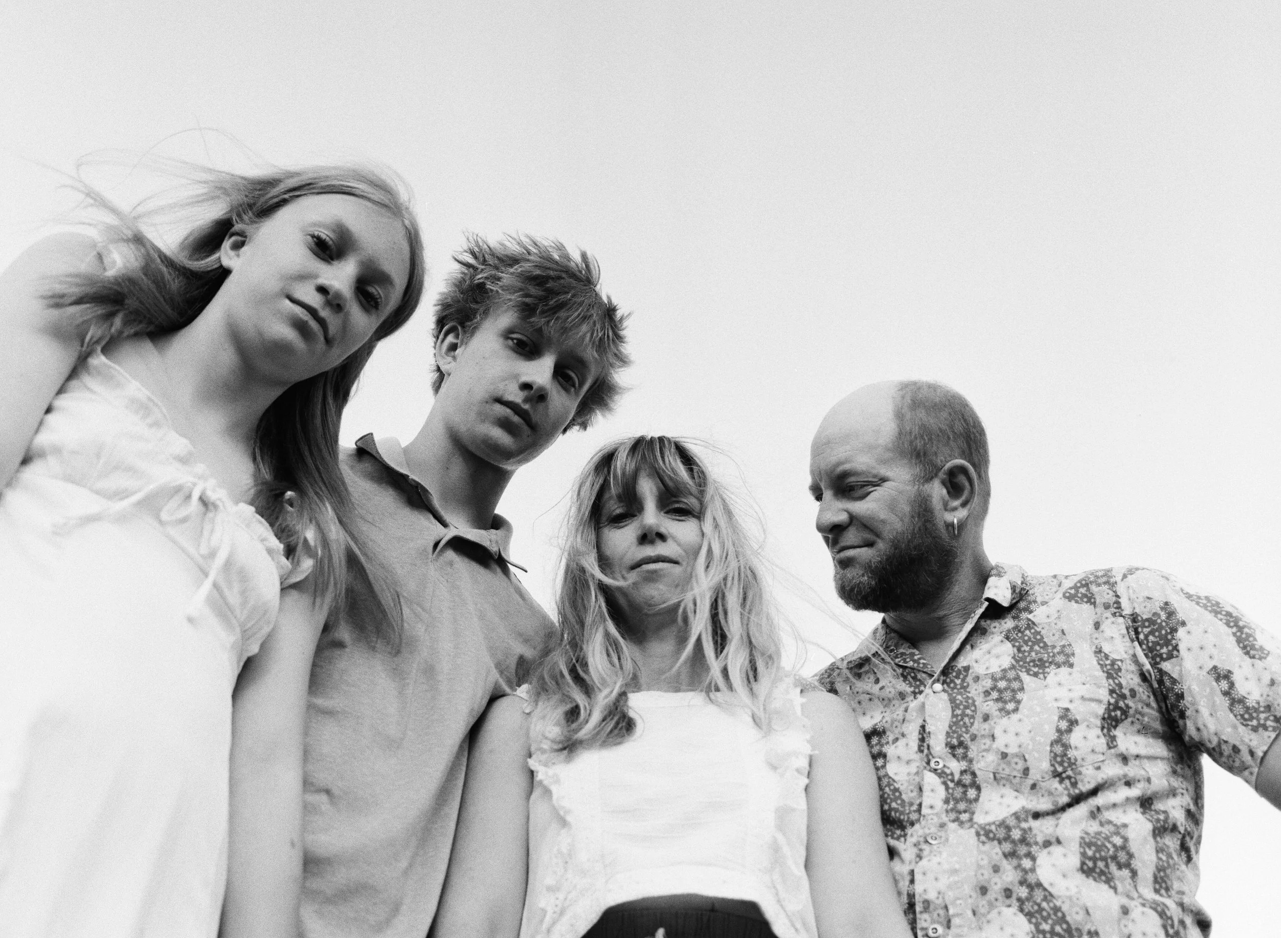 Family of 4 with two teenage kids from below looking at eachother and at the camera