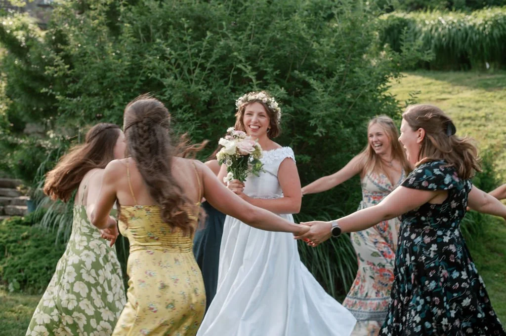 A bride stands in the middle of a group of friends twirling around her in motion blur during a wedding in rhode Island