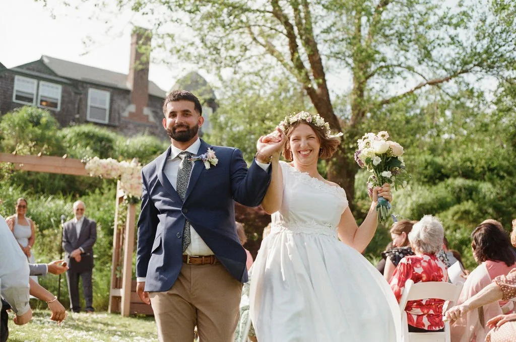 a couple walks down the aisle after their wedding celebration in a backyard wedding in newport rhode island on film