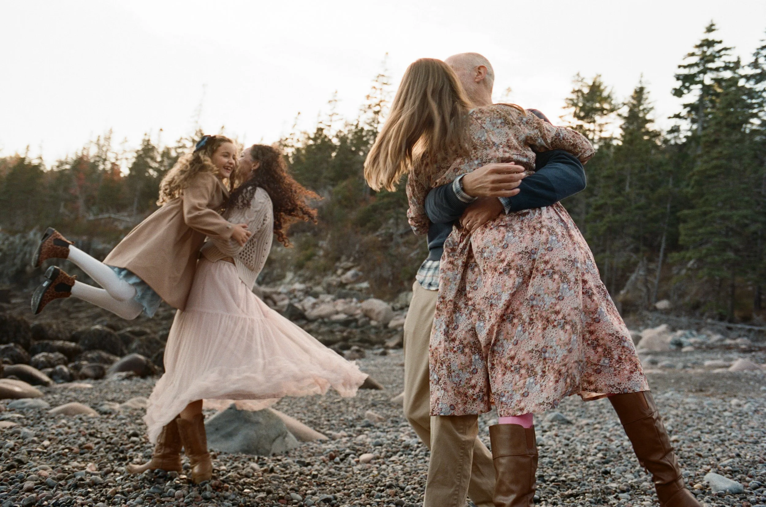 Maine family photography with parents spinning their daughters at a rocky beach in maine