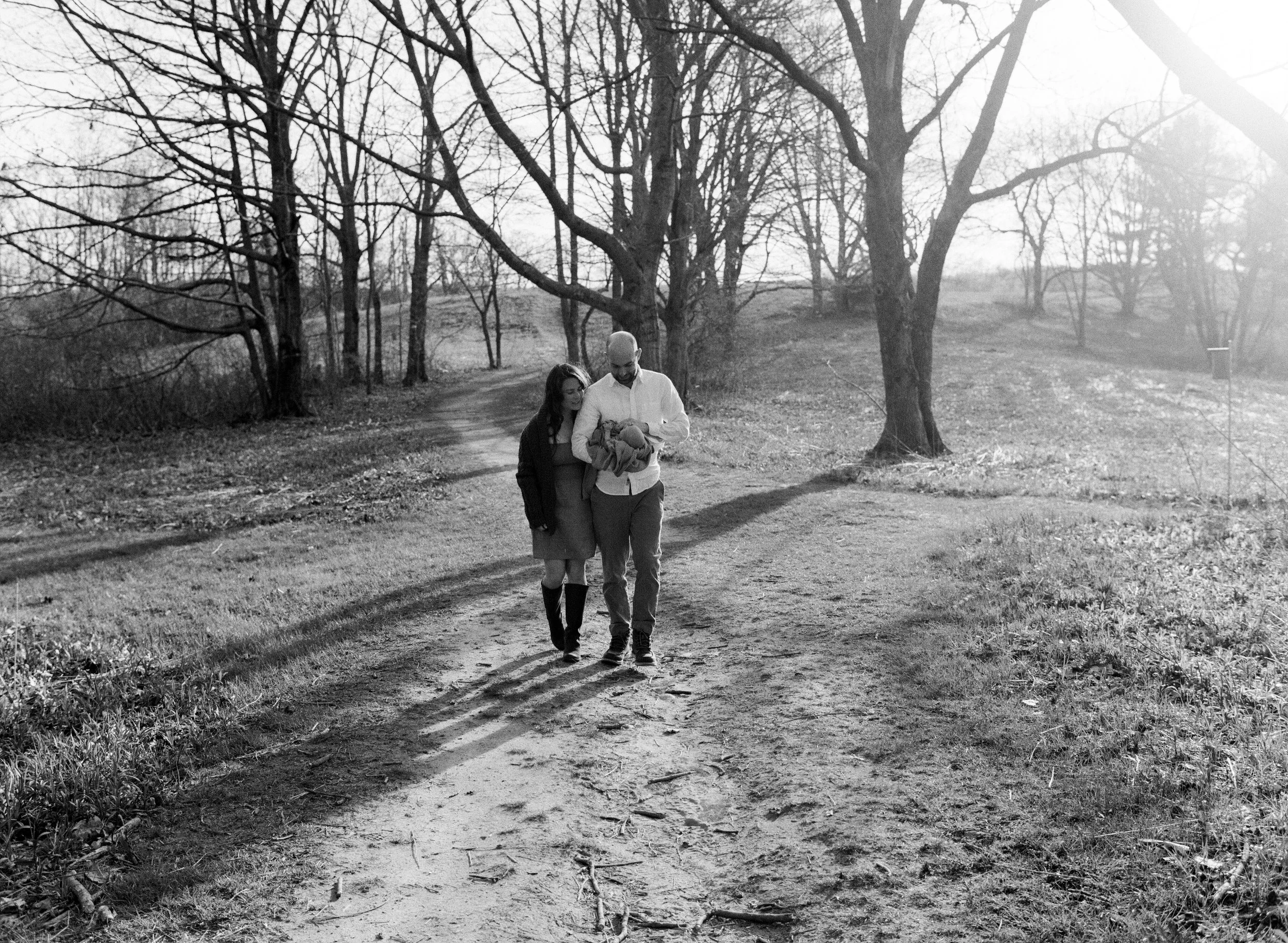 family walking up forest path during newborn session in falmouth maine