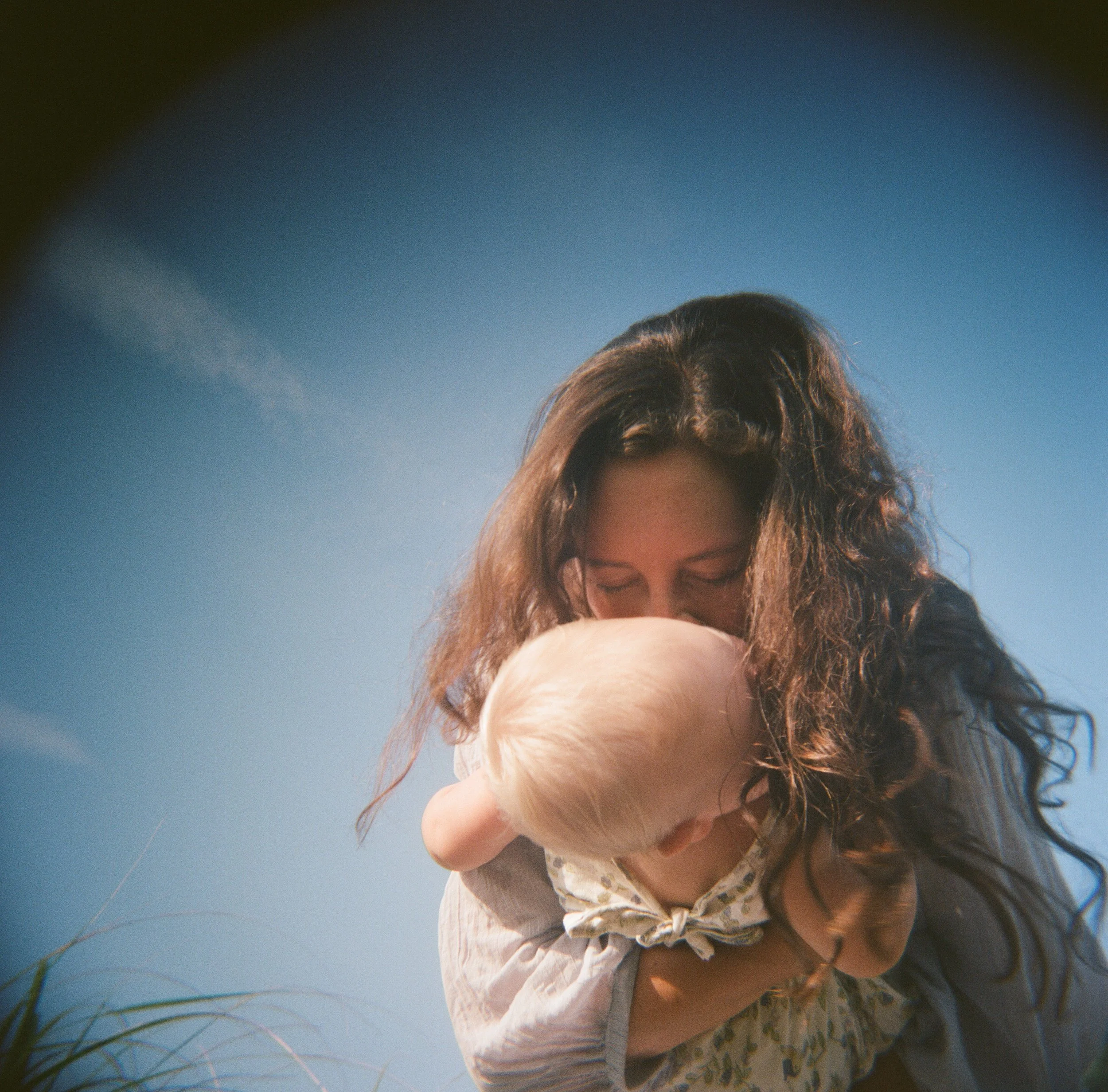 A mother kisses her daughter in this fun film photography session near Bath Maine