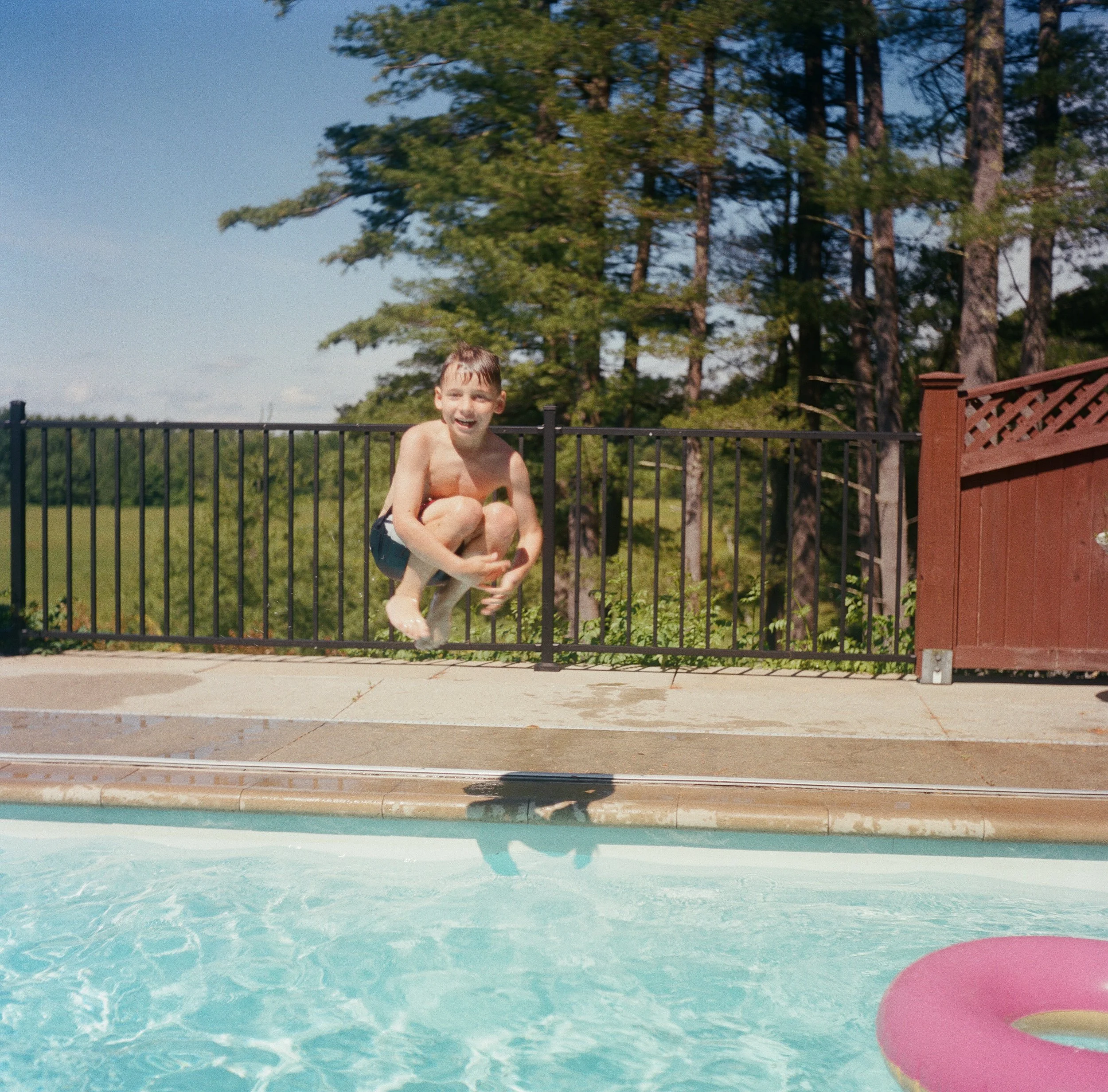 Candid family photography session in Bath Maine of a kid jumping into a pool