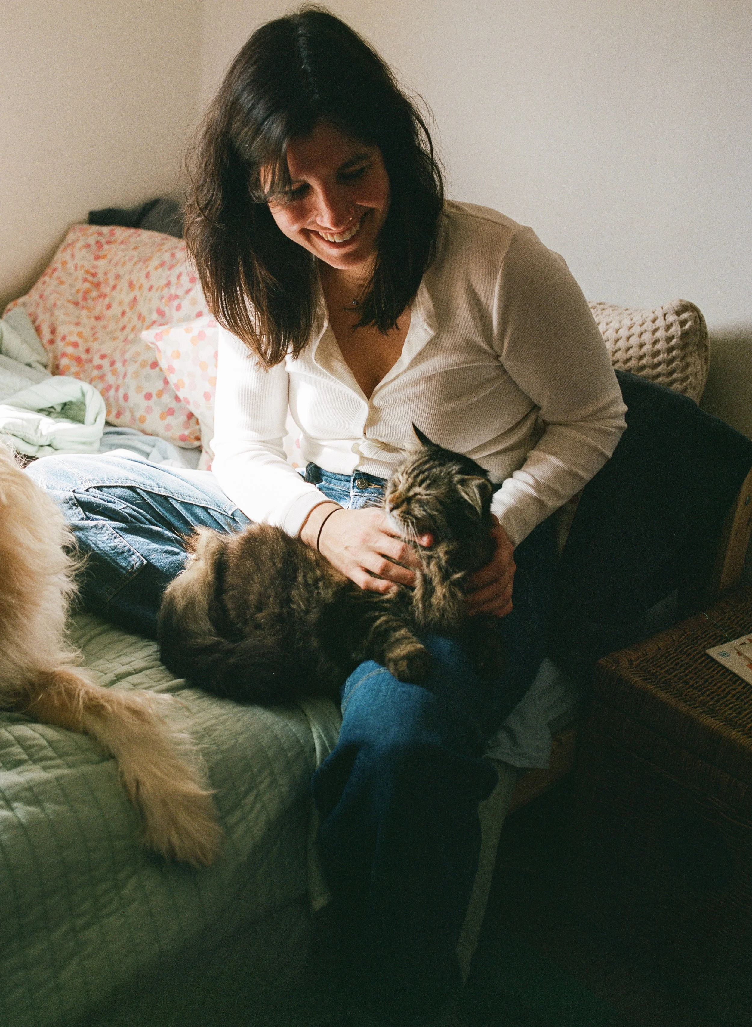 Family session at home in midcoast maine, a mother sits on the bed with her cats on film