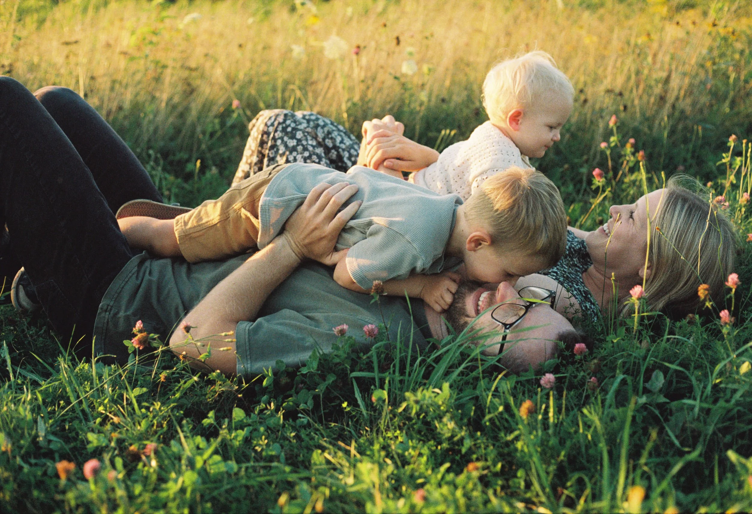 a family lying in grass at sunset smiling and laughing during session in rockland maine
