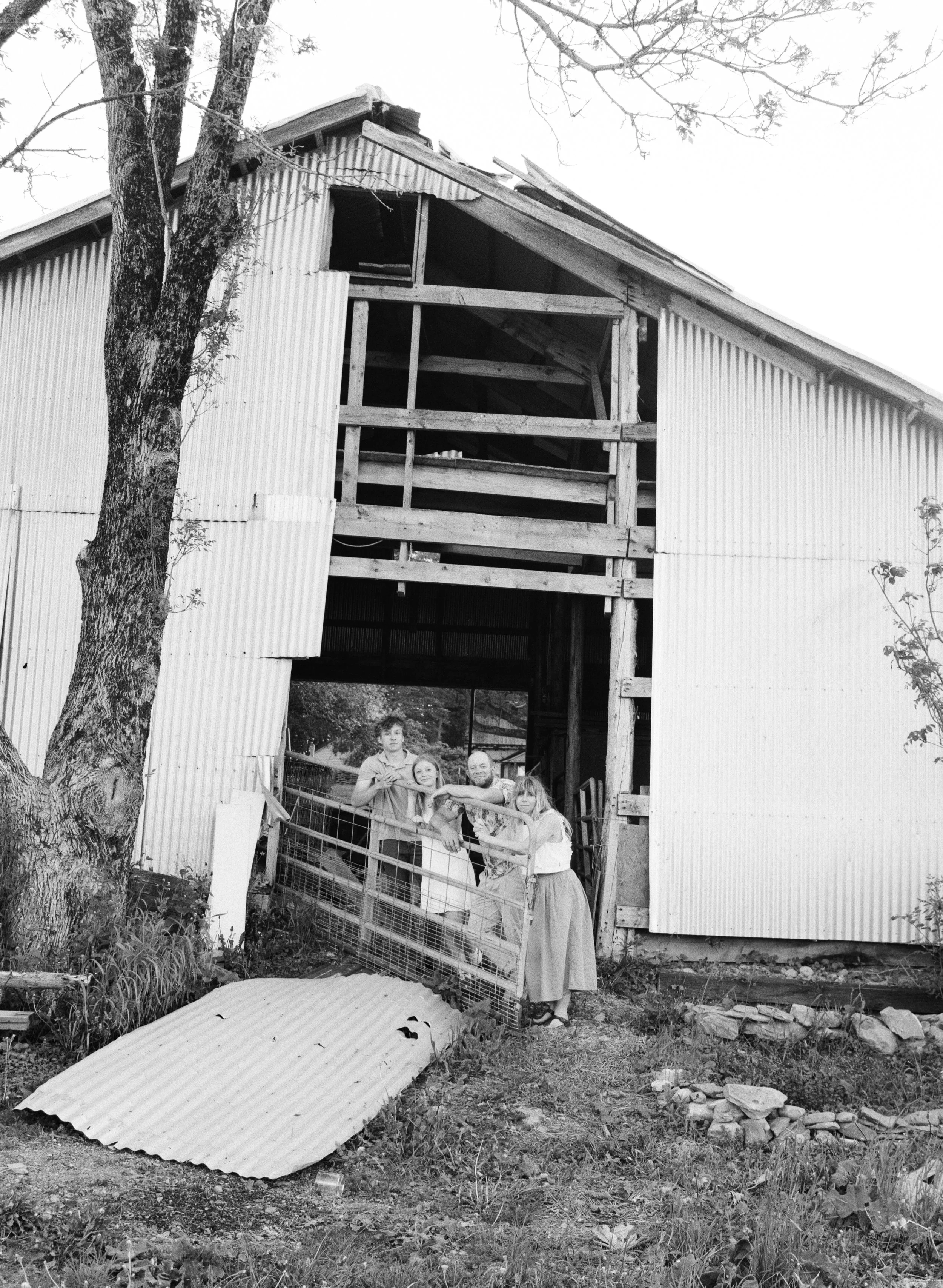 A family stands at their barn at home in rural bangor maine during a family photography session