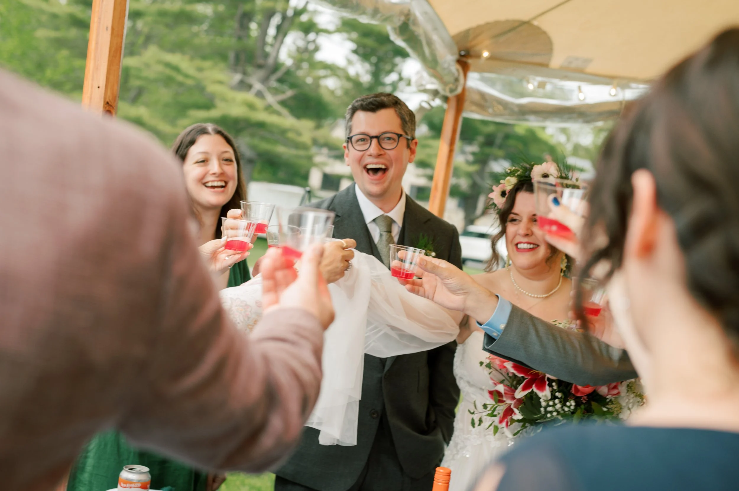 Bride, groom, and guests cheersing and drinking champagne before their outdoor backyard wedding ceremony in souther maine
