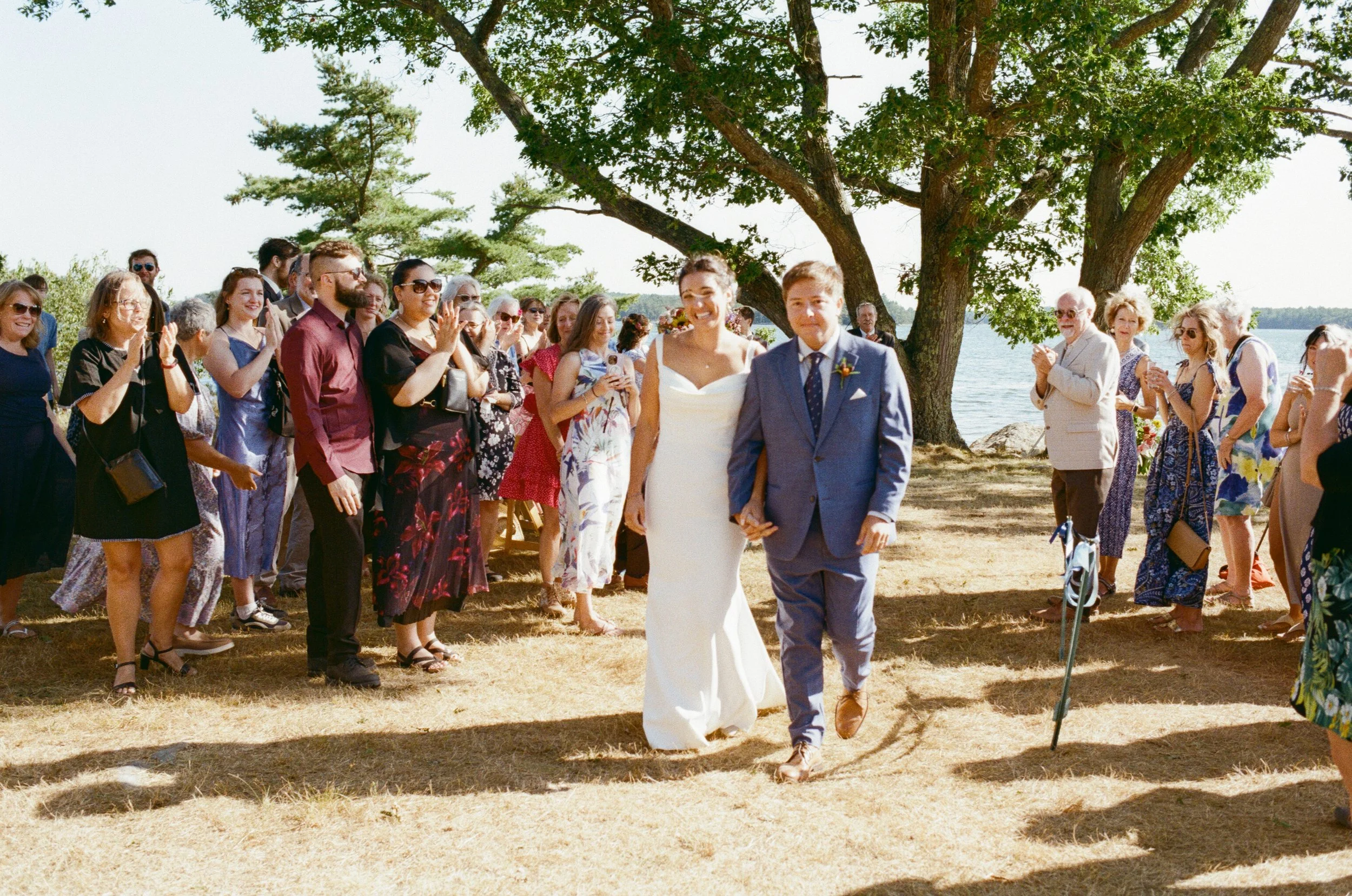 maine wedding film photographer bride and groom exiting outdoor ceremony during backyard wedding in midcoast maine