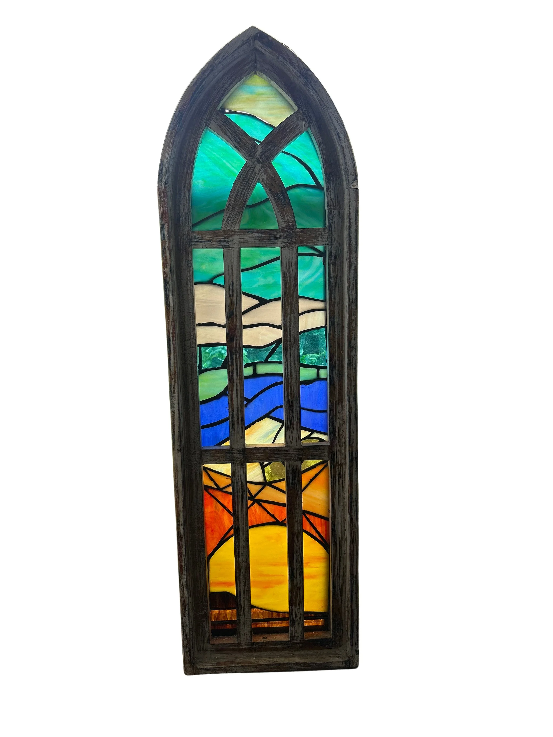 A stained glass window with an arched shape, depicting a colorful landscape scene with a sunset, fields, and sky, framed by a dark wooden border.