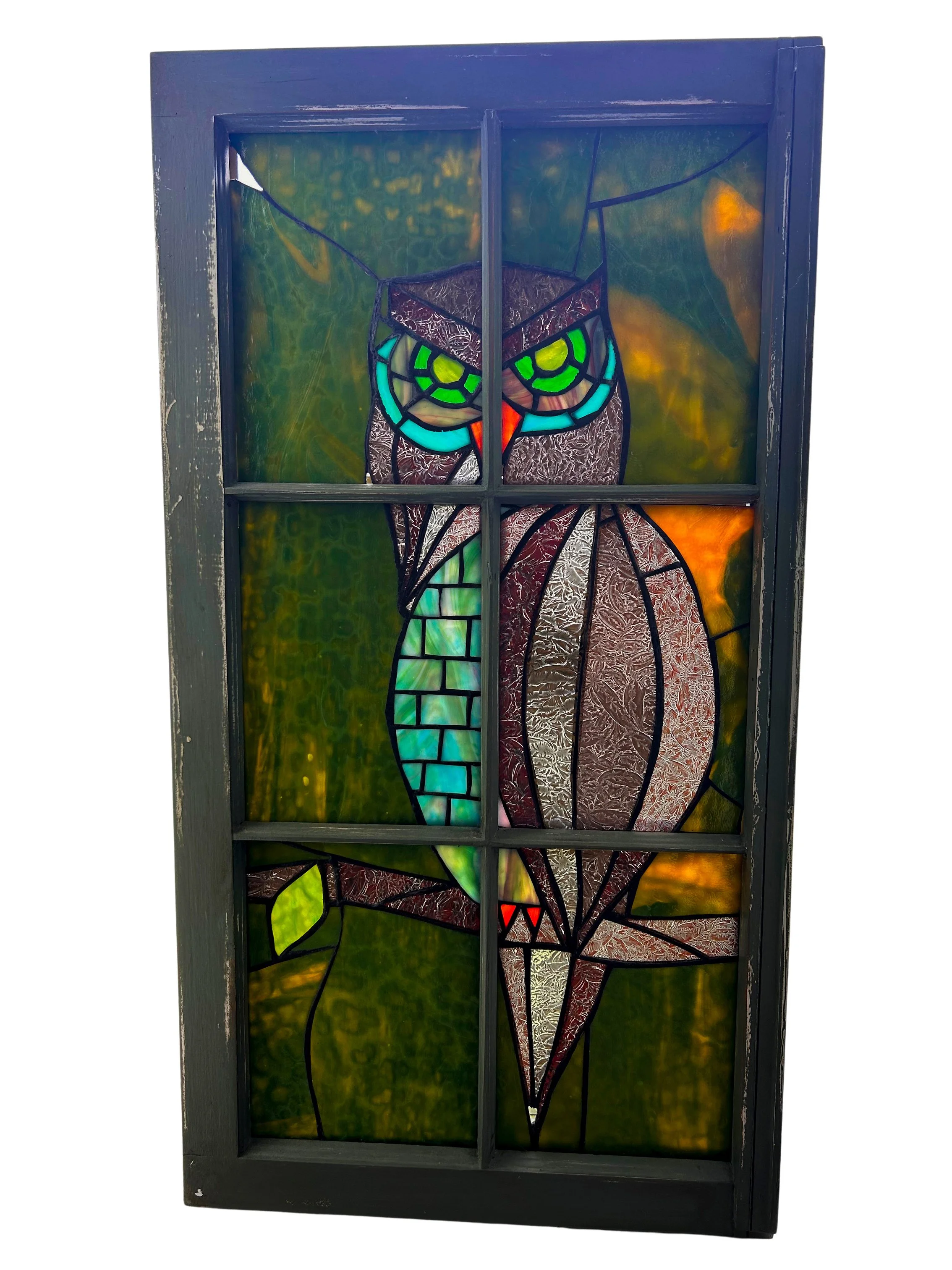 Stained glass window depicting a colorful abstract design with green, orange, red, and gray hues in a black wooden frame.