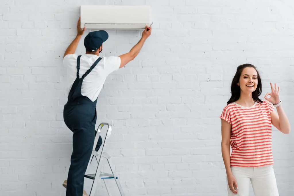 stock-photo-smiling-woman-showing-gesture-while-repairman-fixing-air-conditioner.jfif