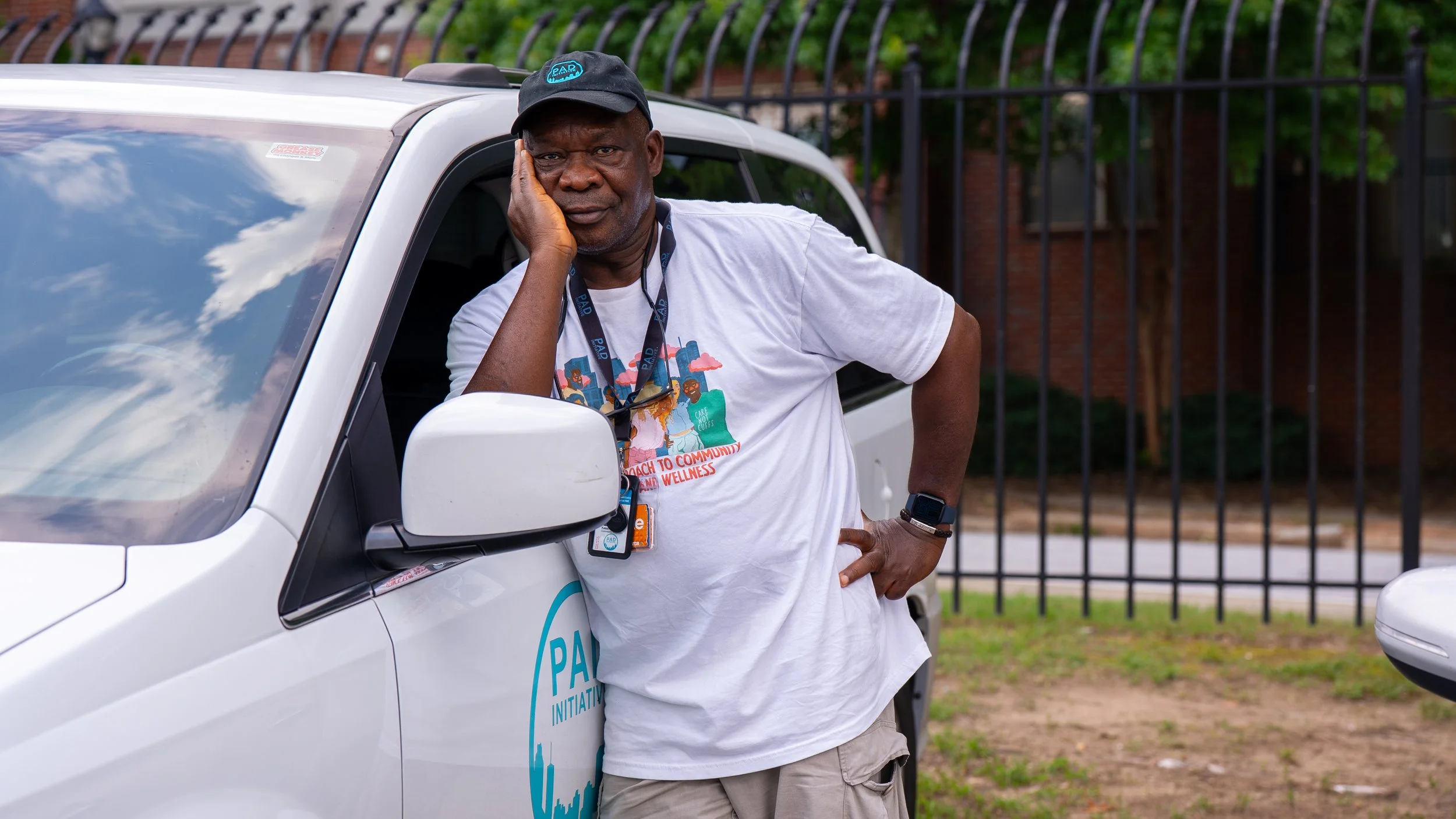 Image features Kasali Obanoyen, Community Responder Team Lead at PAD. Kasali is wearing a white PAD T-shirt and cap and leans against a white PAD van with his hand on his face.