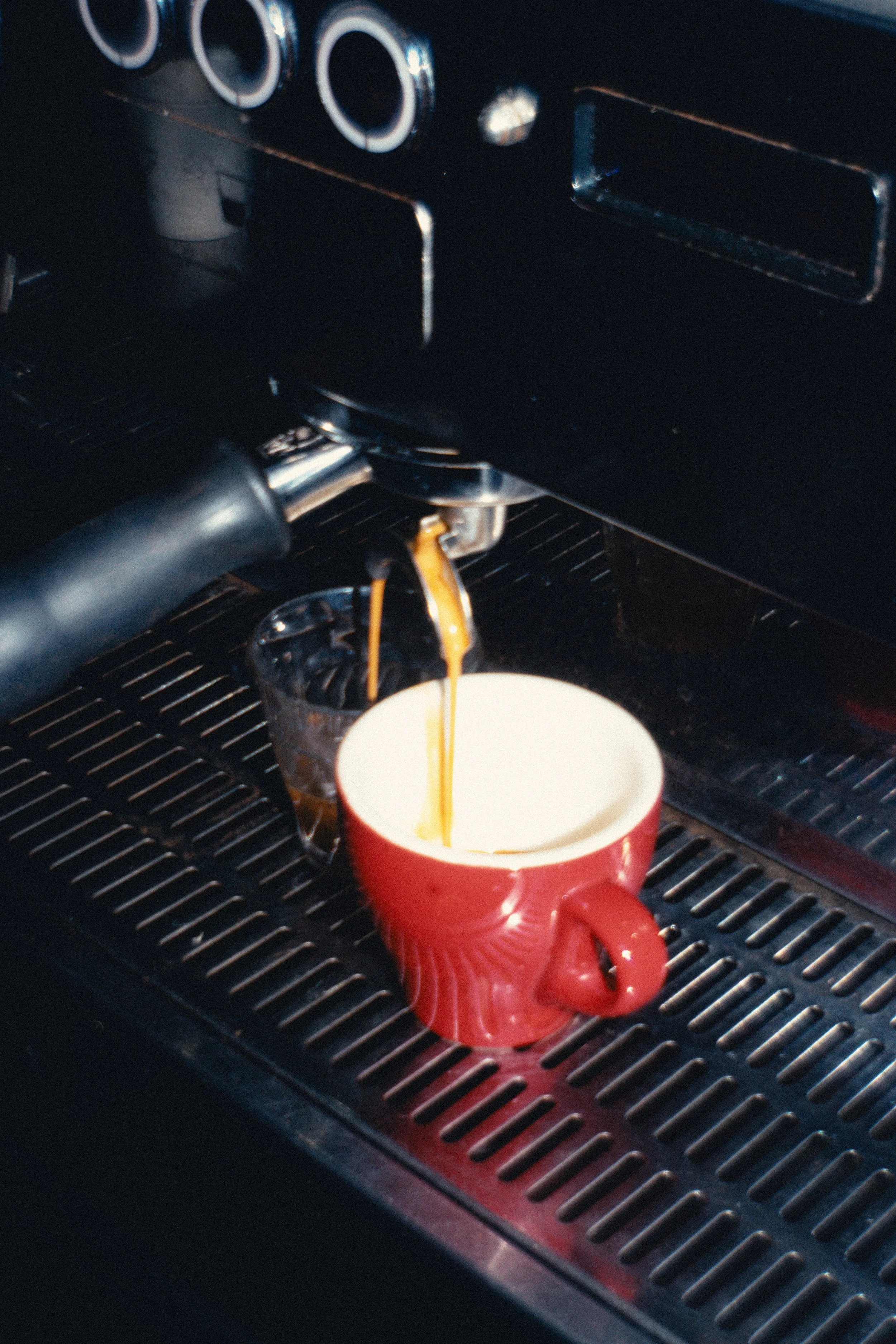 Espresso machine dispensing coffee into a red cup