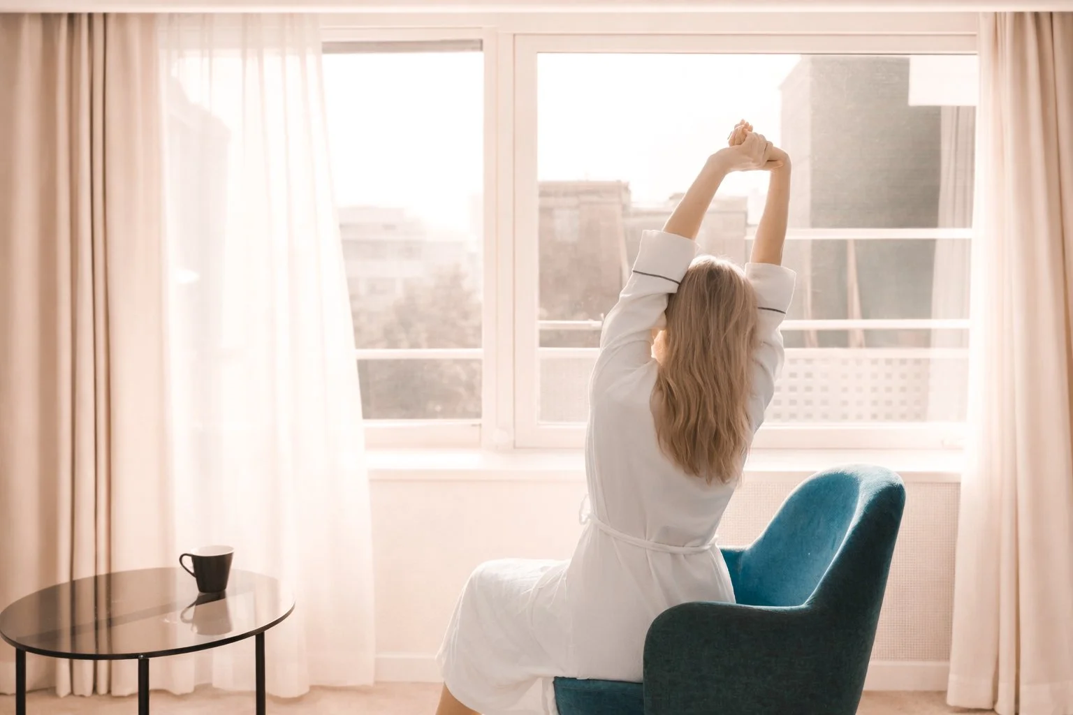 woman stretching in a luxury hotel room with morning coffee