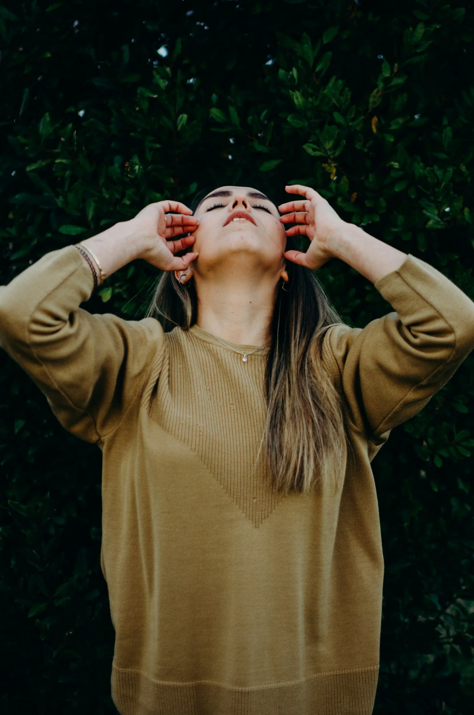 Woman standing outside with her head back and hand moving through her hair, taking a deep breath during a moment of stress relief