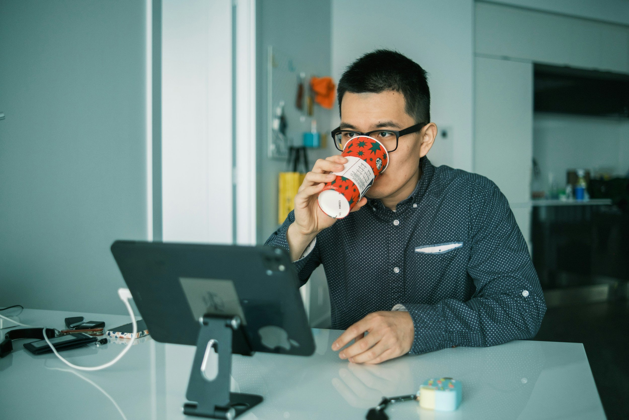 Man sitting at his desk sipping coffee while working at his computer, representing the pressure of family expectations and cultural obligations explored in therapy in Northern Virginia