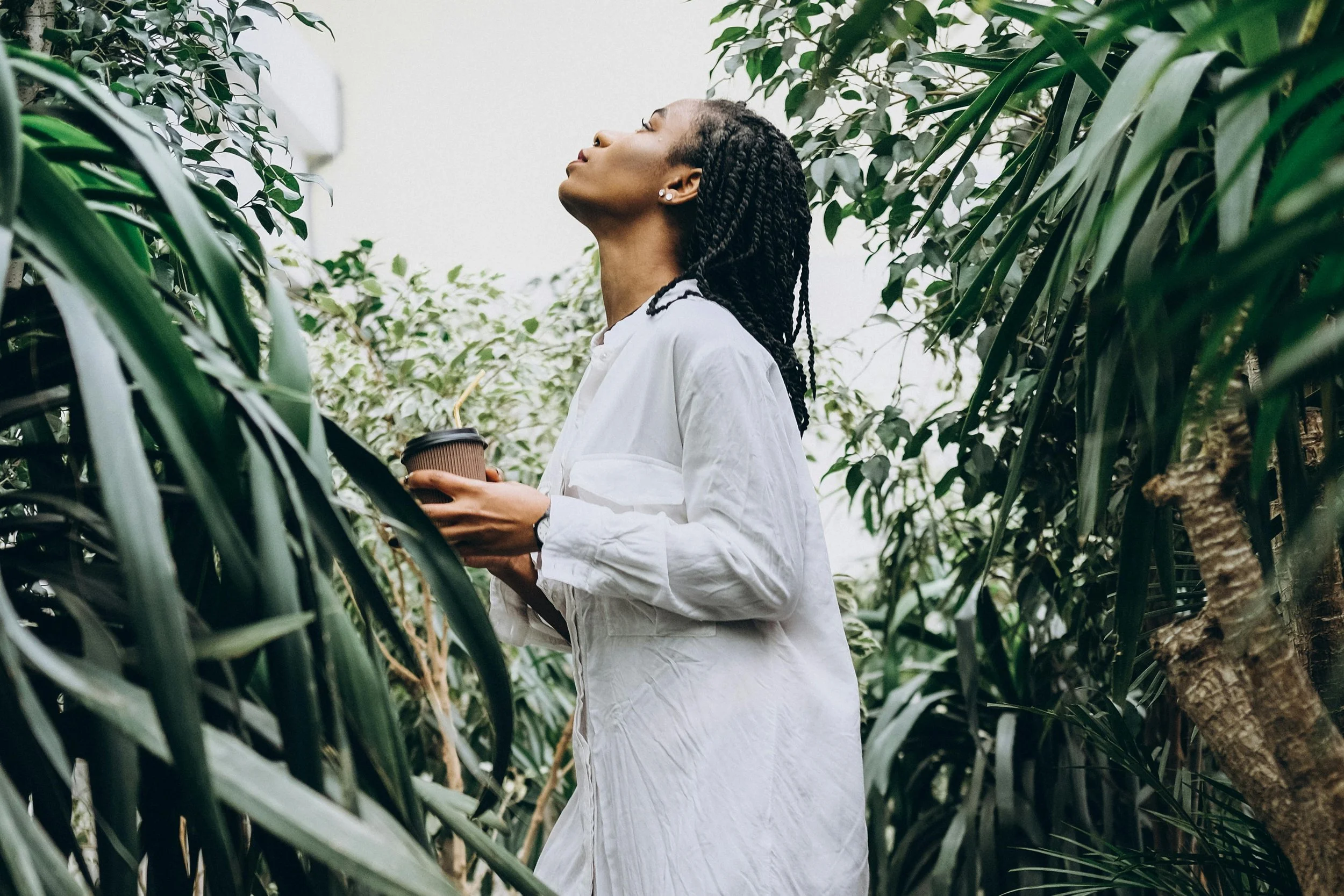 Woman standing near greenery outside, taking a deep breath, representing healing from perfectionism through therapy in Virginia