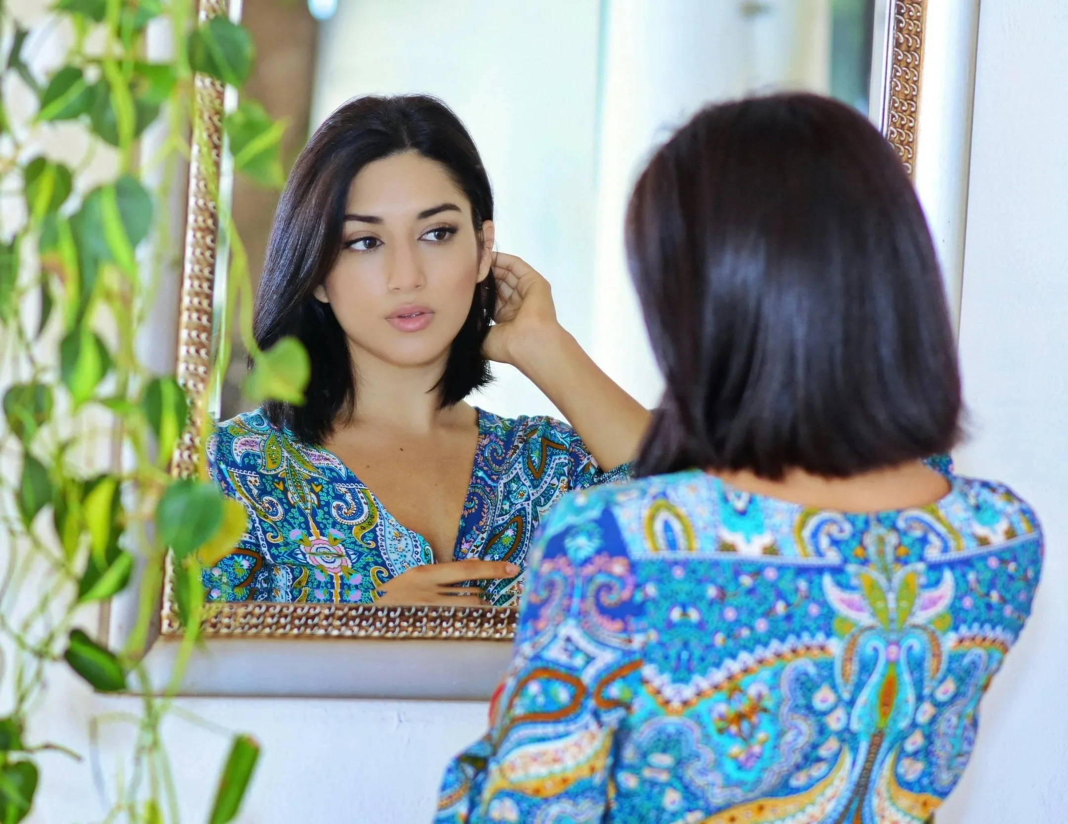 Woman looking at her reflection in a mirror, representing self-reflection and identity in childhood trauma therapy for adults in Northern Virginia