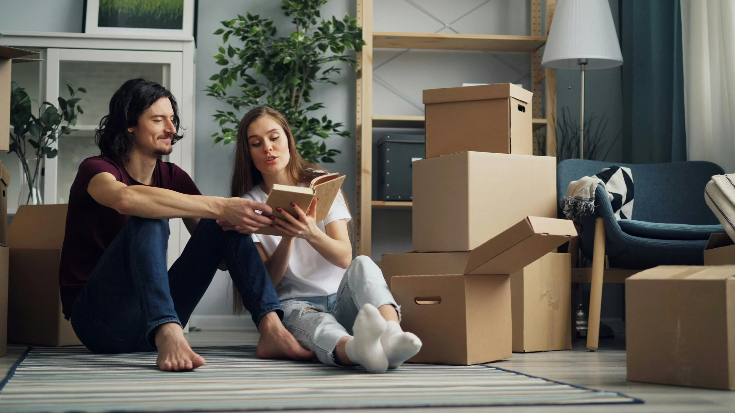 Man and woman sitting on the floor together looking at a book, representing the collaborative and exploratory process of trauma therapy