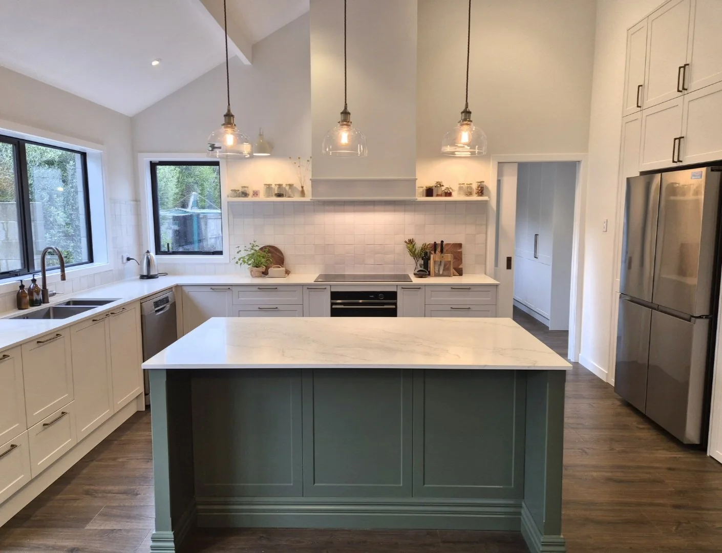 Modern kitchen with large island, stainless steel appliances and pendant lighting.