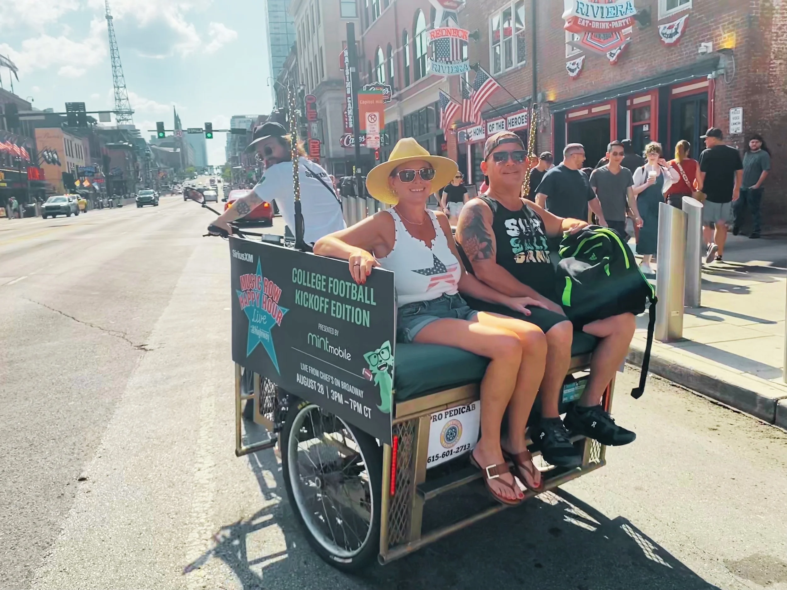 Guests riding a Pro Pedicab during the SiriusXM and Mint Mobile activation on Broadway in Nashville