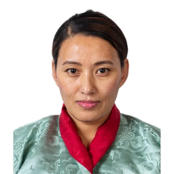 A woman with short dark hair, wearing a green patterned gown and a red silk scarf around her neck, looking directly at the camera with a neutral expression.