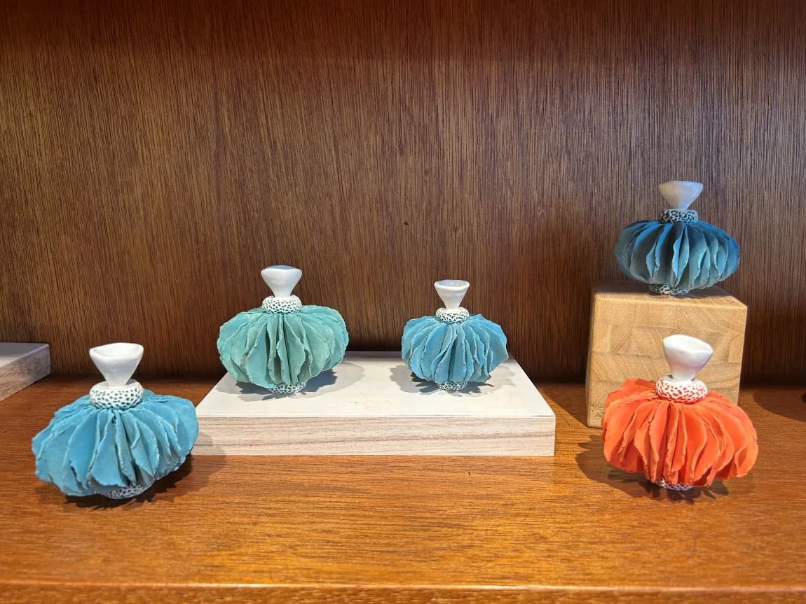 Handcrafted ceramic hula girl by Jennifer Hill, adorned in vibrant blue, orange, and teal colors, capturing the spirit of Hawaiian culture with intricate details and a playful, artistic style.