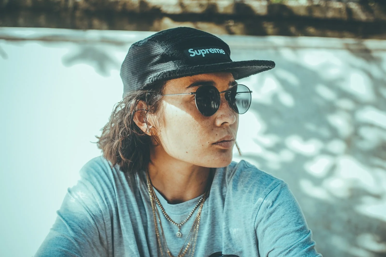 Model in grey t-shirt gold jewellery and sunglasses in skate park