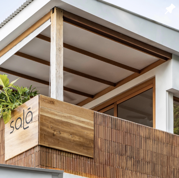 Exterior view of a modern building with a wooden and brick balcony, and a sign that reads "sala".