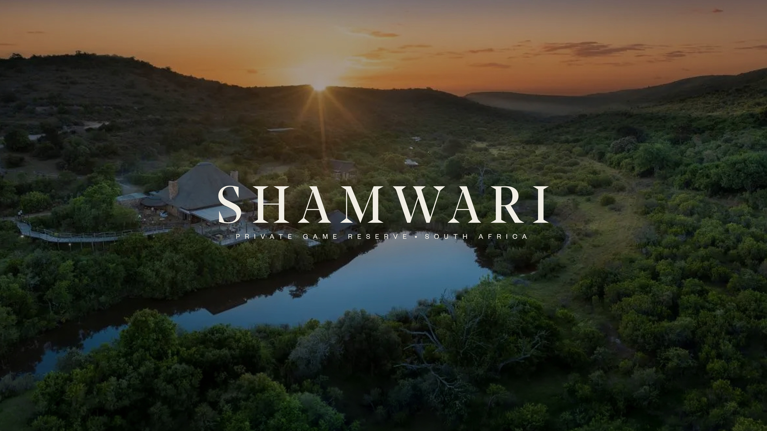 Aerial view of a landscape with a river, green trees, hills, and a house at sunset, with text overlay reading 'Shamwari Private Game Reserve South Africa'.