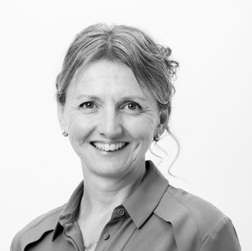 Black and white portrait of a smiling woman with short hair, wearing a collared shirt.