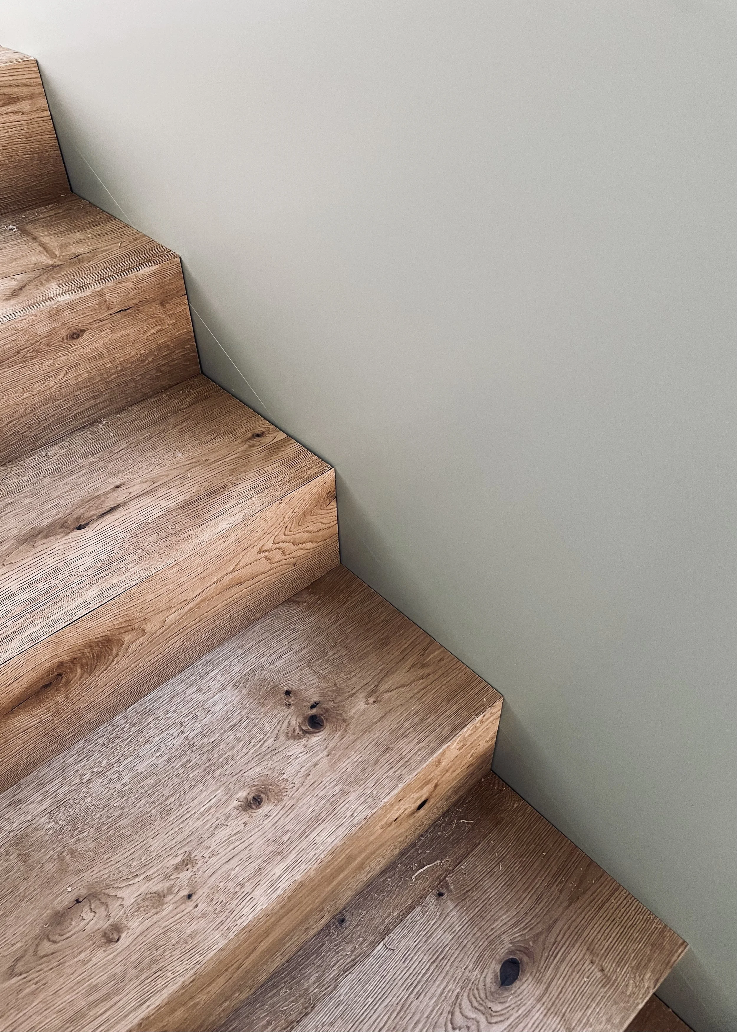Treppenstufen aus Holz neben einer hellgrauen Wand.